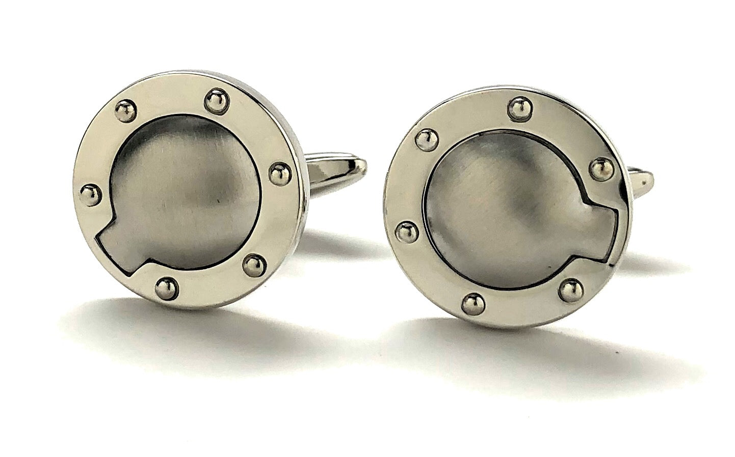 Pair of silver cufflinks with circular design on a white background