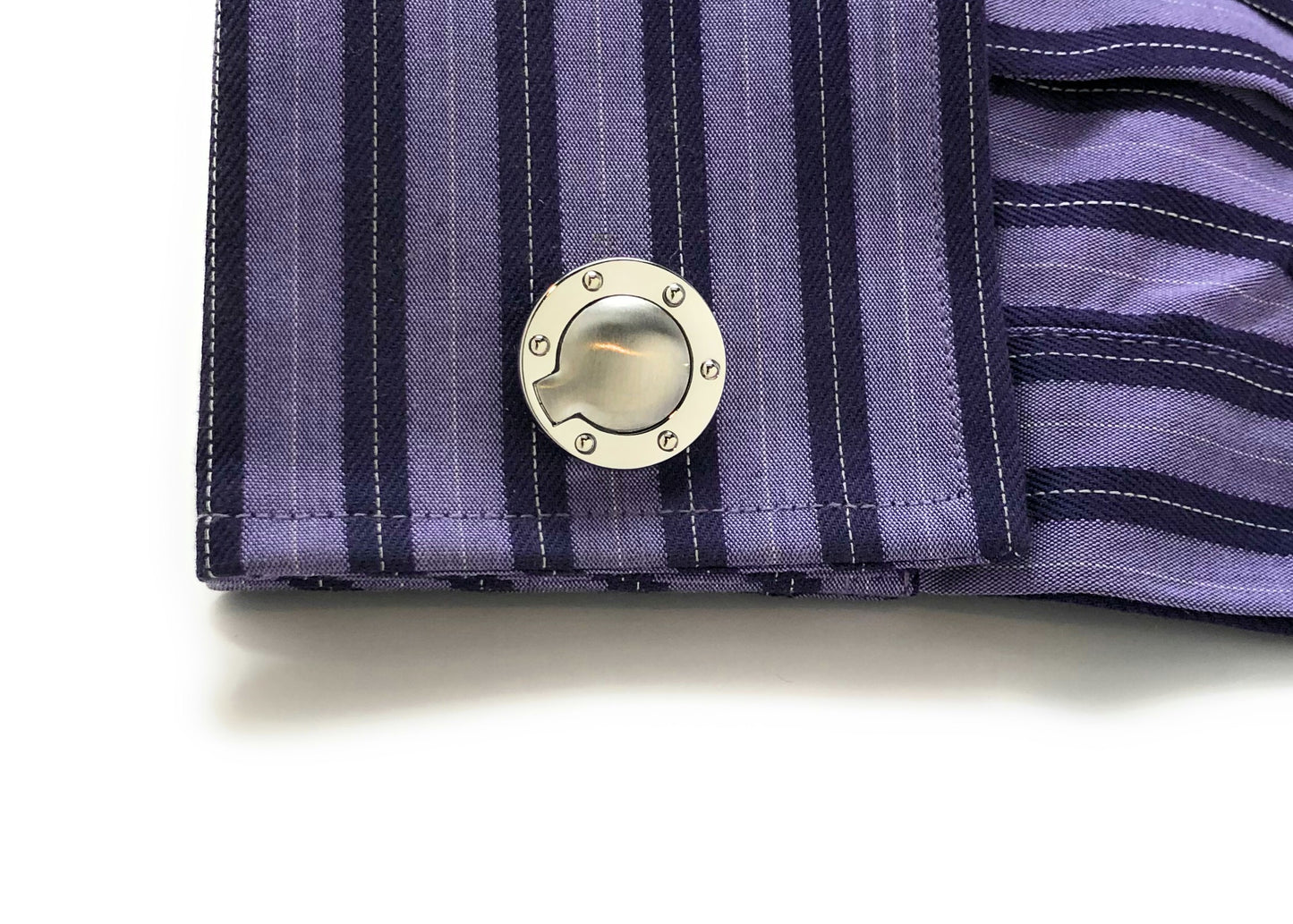 Close-up of a cufflink on a striped shirt sleeve with a white background