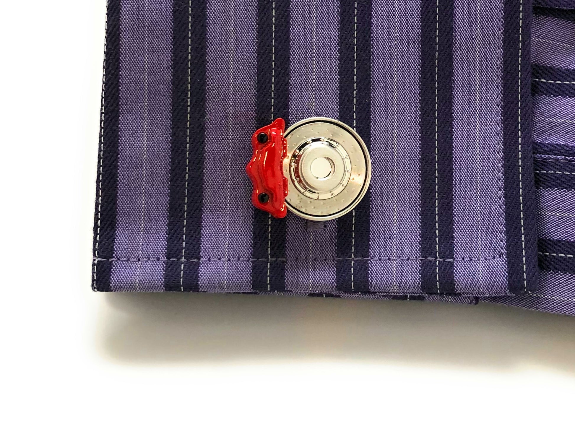 Close-up of a button on a striped shirt with a red accent
