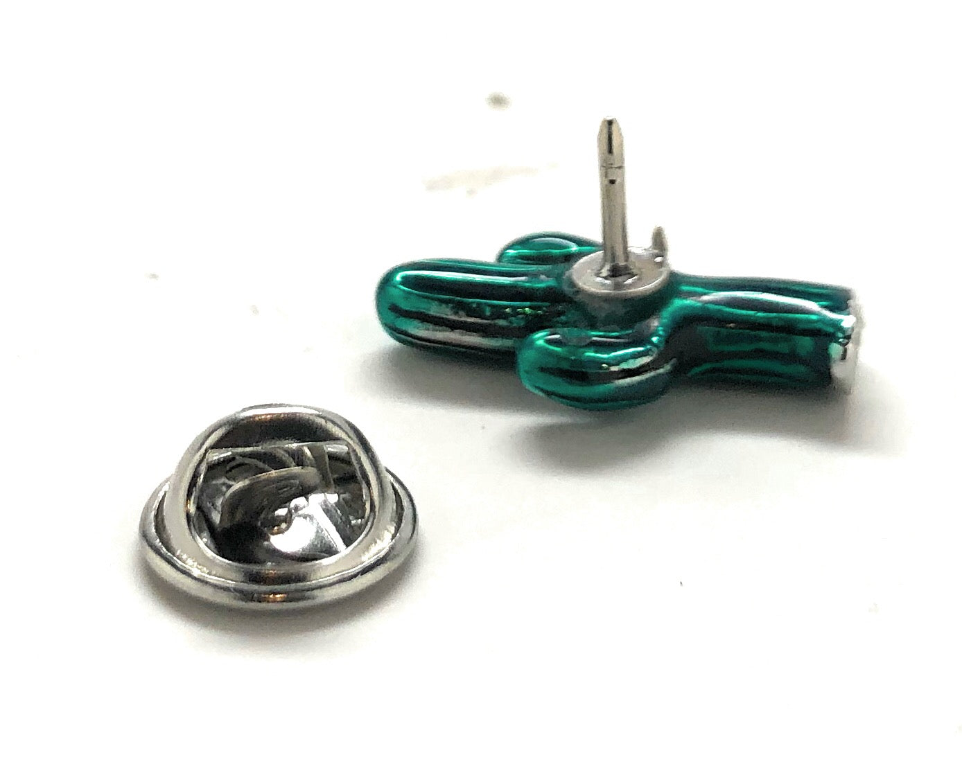 Green and silver cactus-shaped lapel pins on a white background