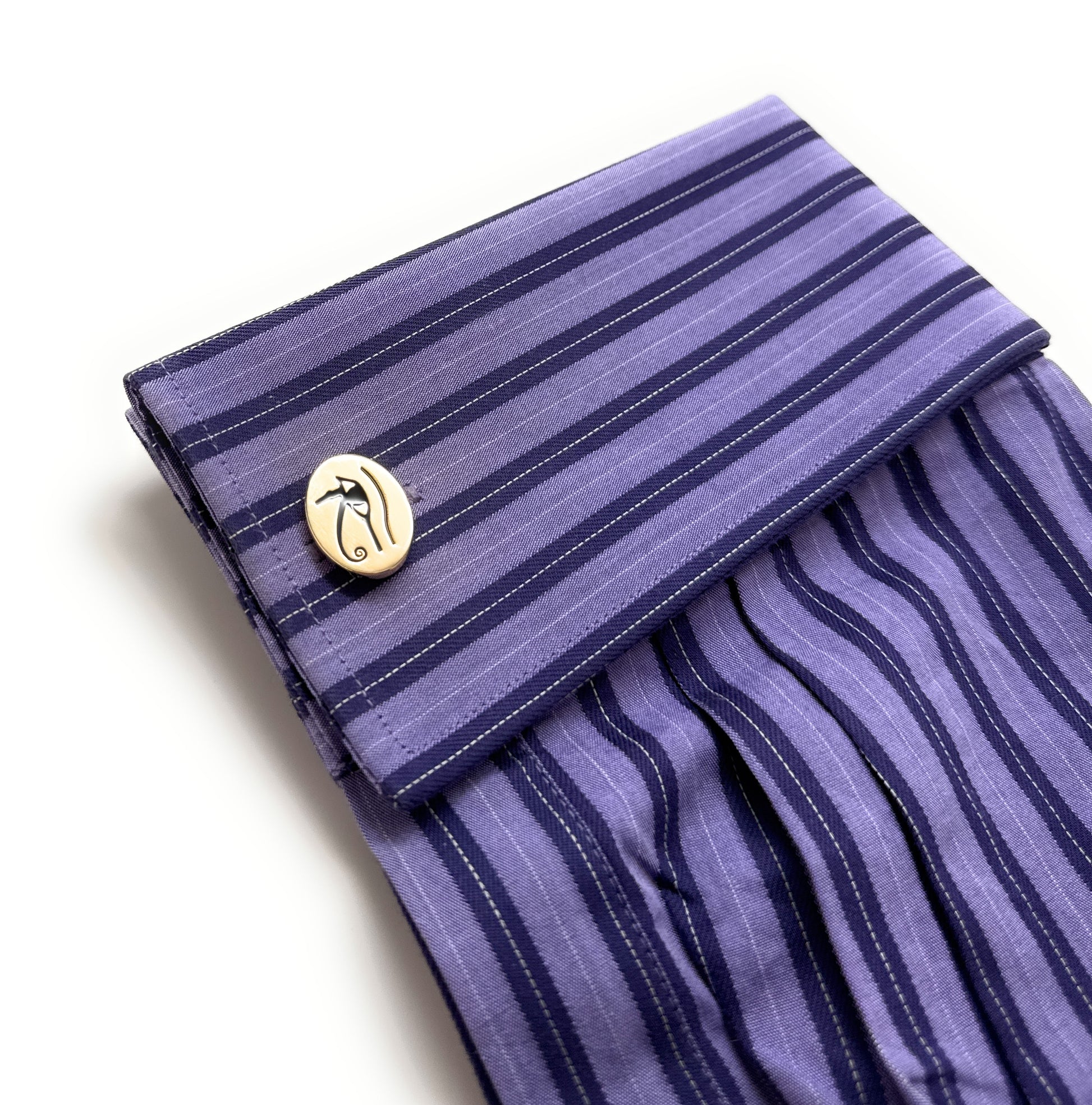 Purple striped fabric with a gold button on a white background