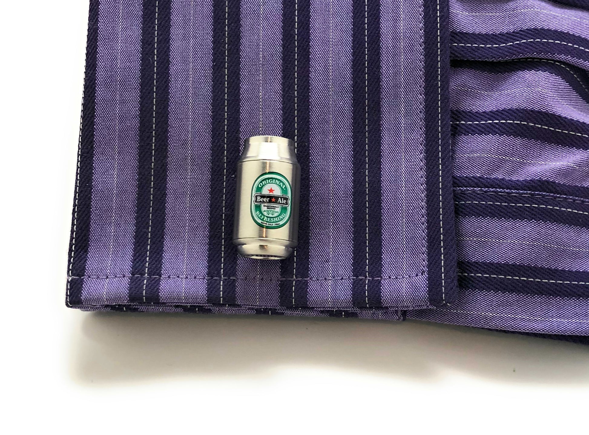 Small metallic object with a green label on a purple striped fabric background