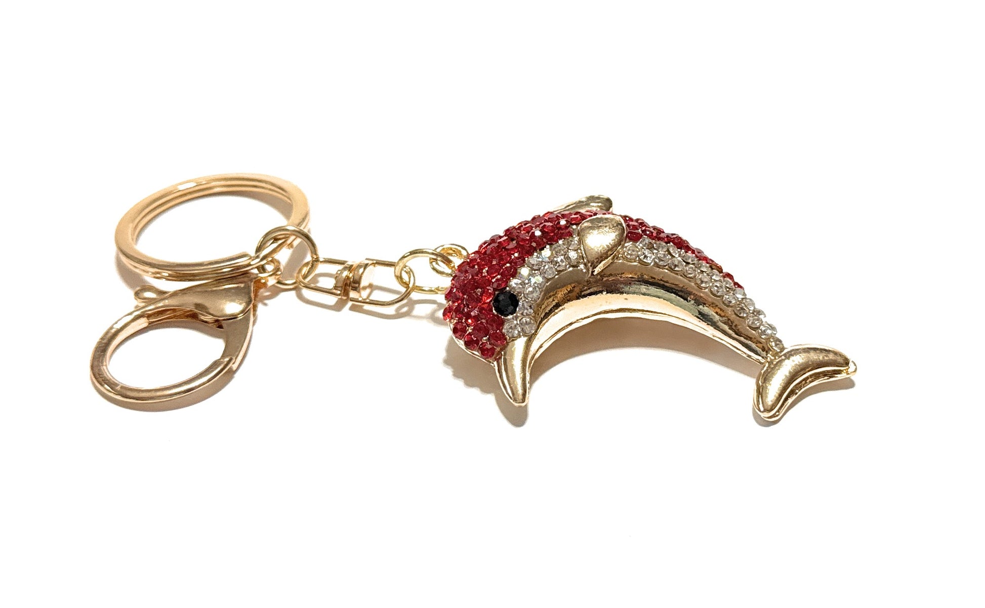 Gold dolphin-shaped keychain with red and black accents on a white background