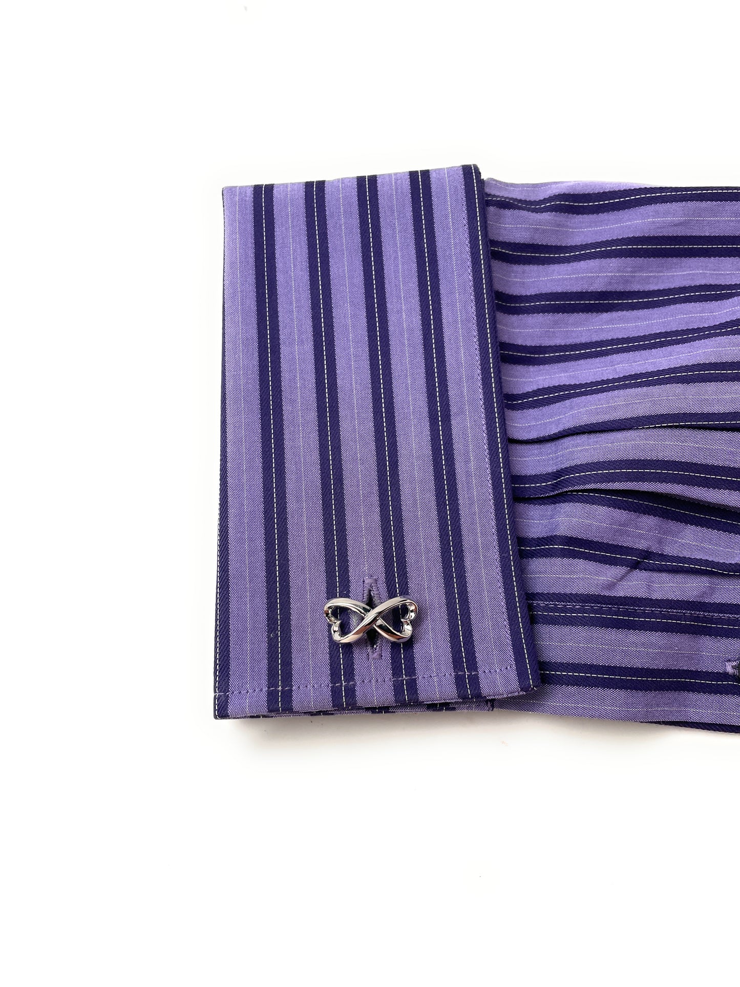 Purple striped shirt cuff with butterfly cufflink on a white background