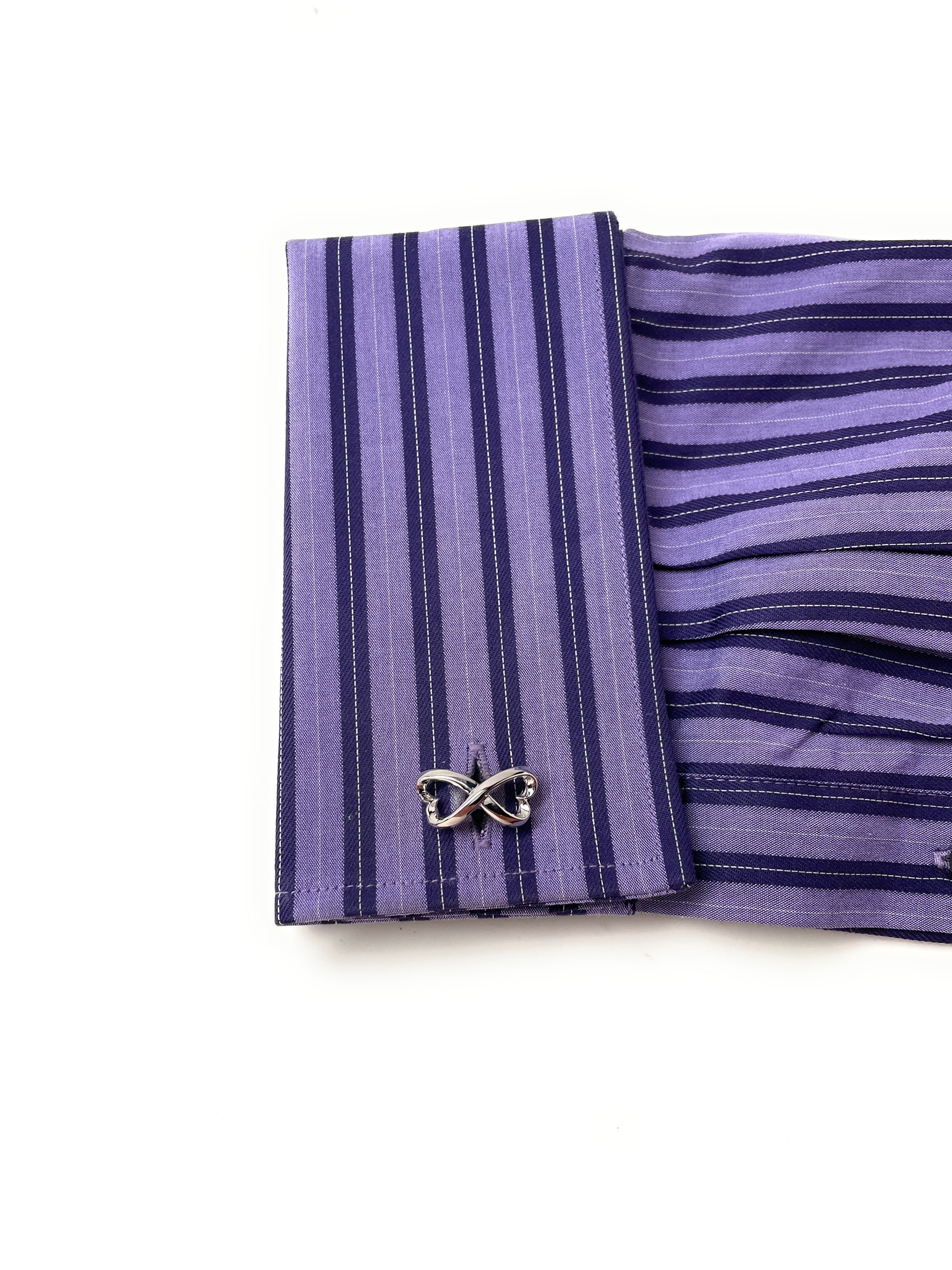 Purple striped shirt cuff with butterfly cufflink on a white background