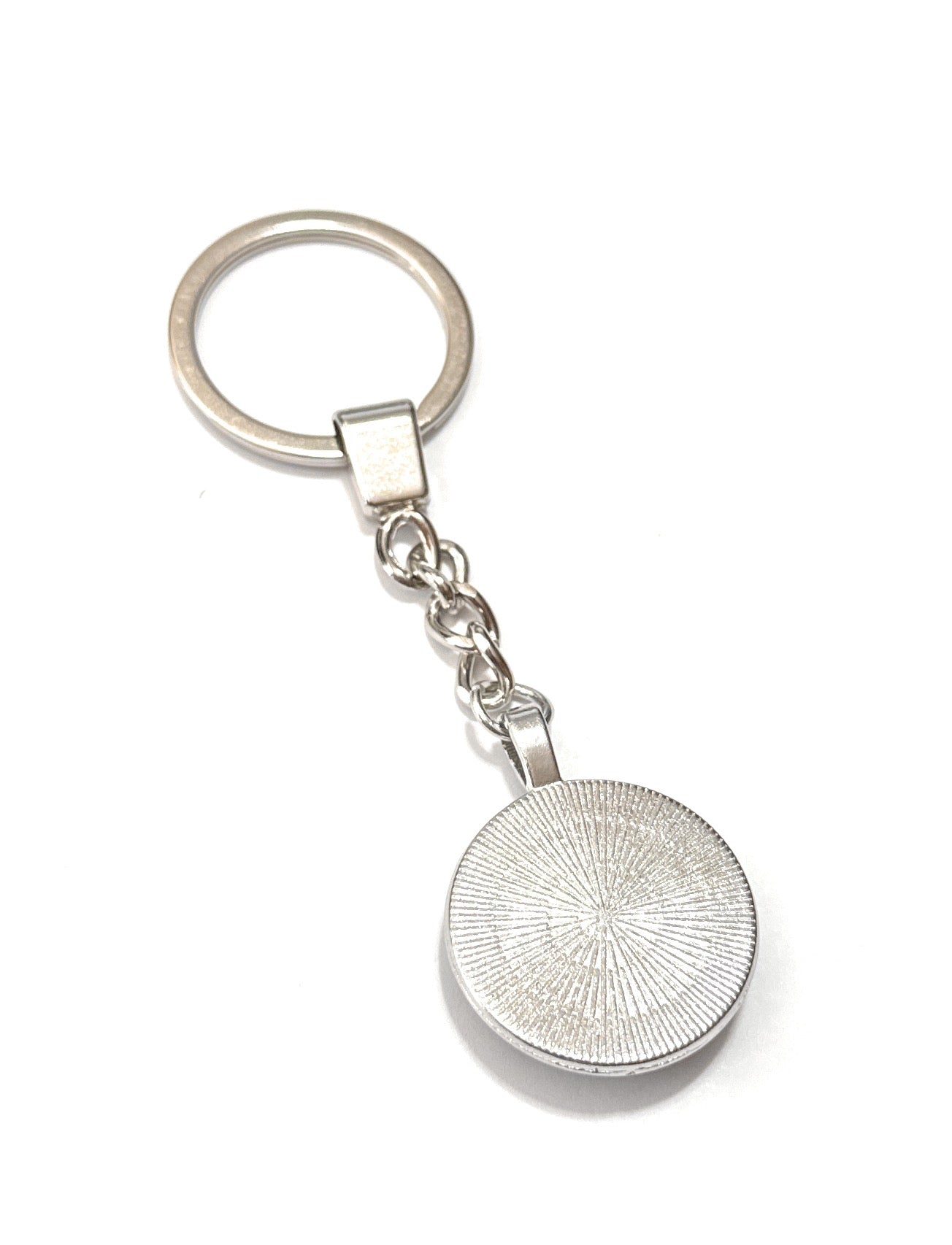 Silver keychain with circular design on a white background