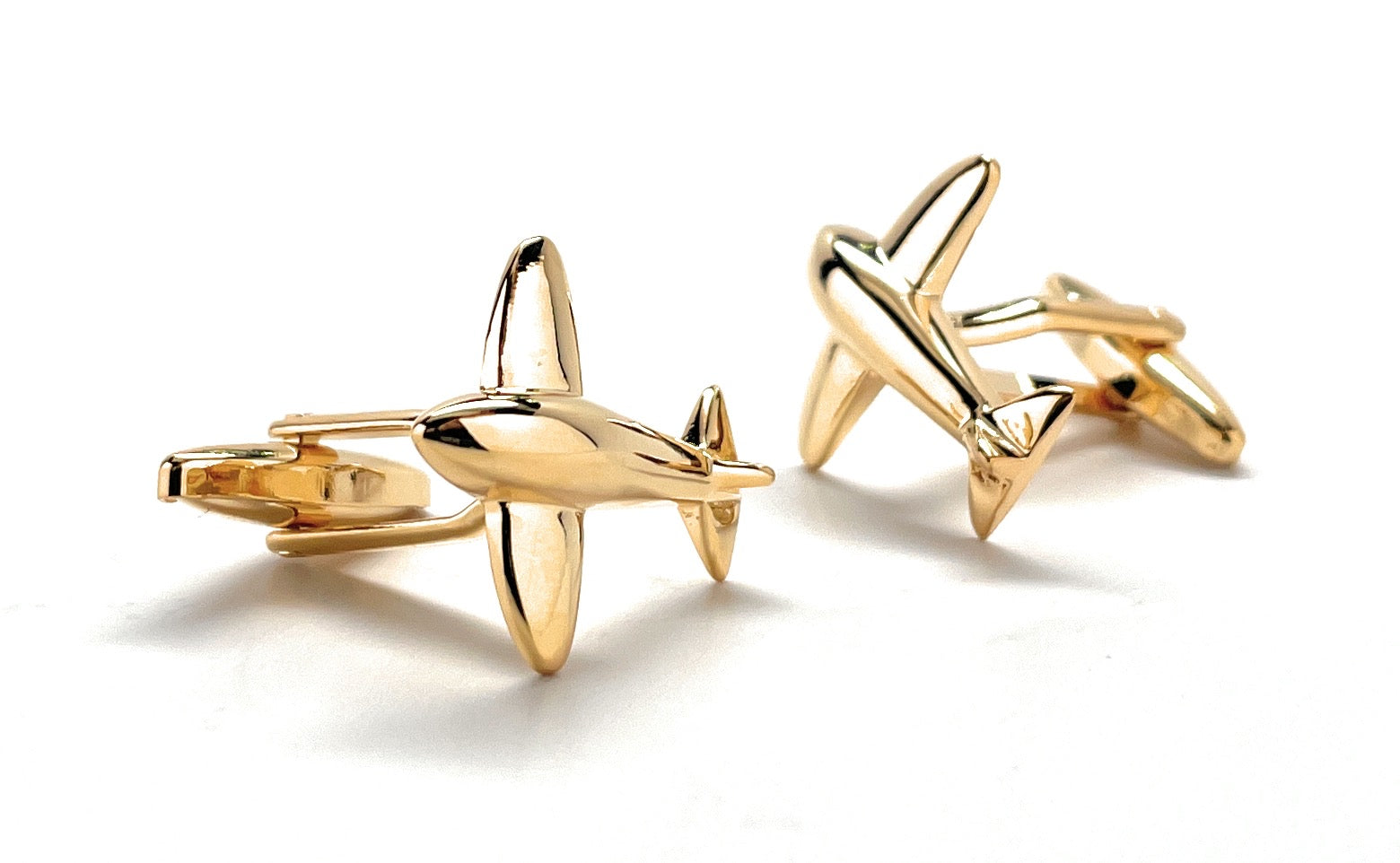 Gold airplane-shaped cufflinks on a white background