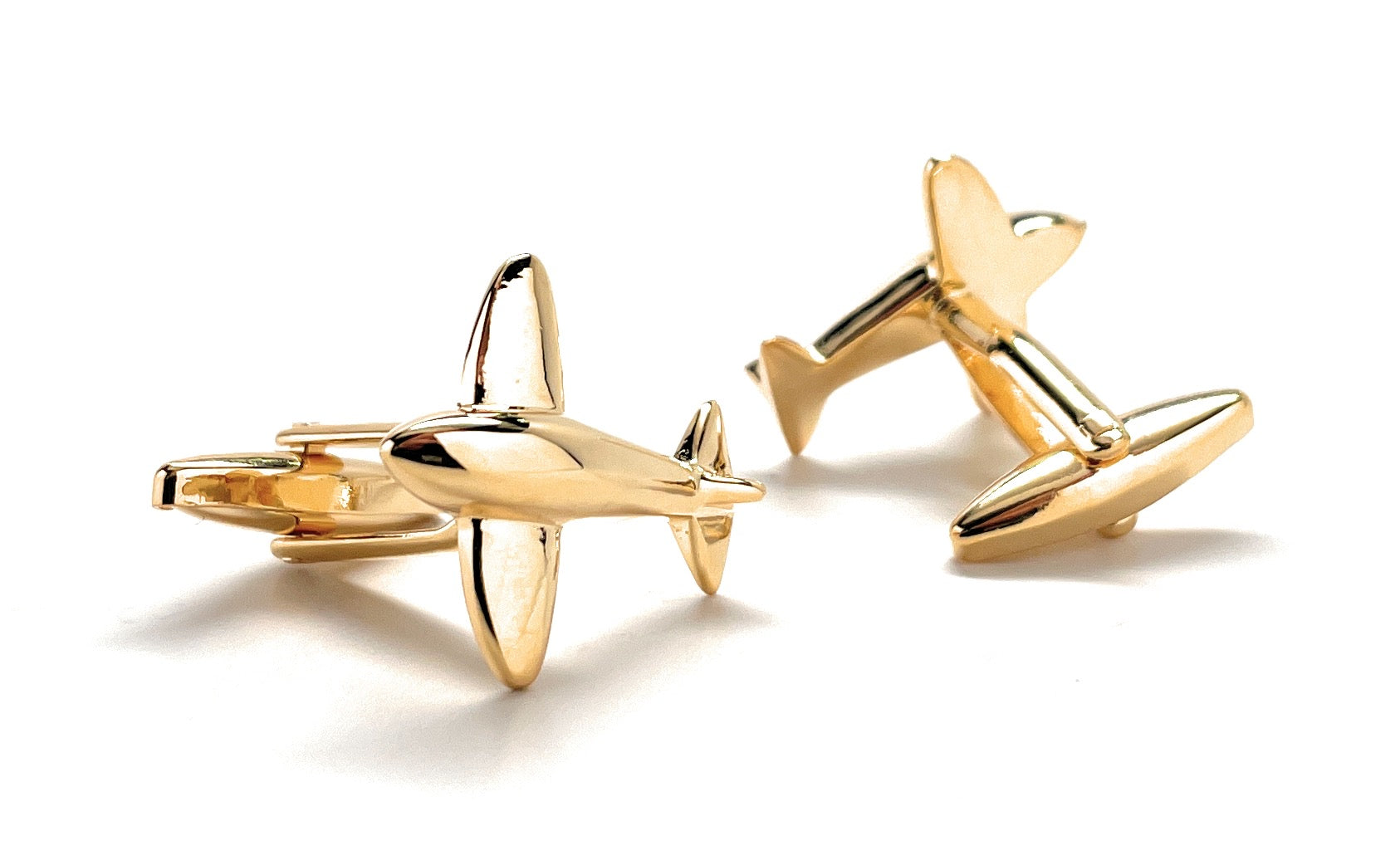 Gold airplane-shaped cufflinks on a white background