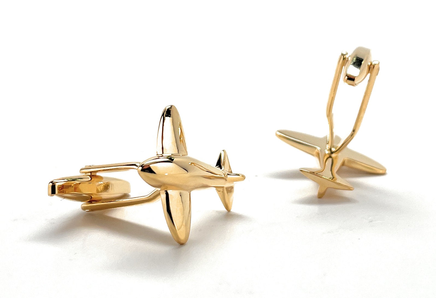 Gold airplane-shaped cufflinks on a white background