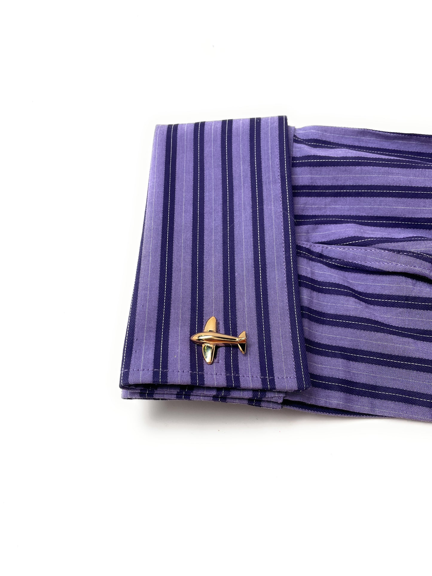 Purple striped shirt cuff with gold airplane cufflink on a white background