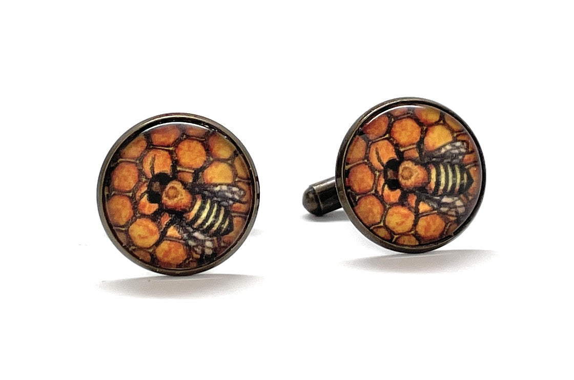 Cufflinks with bee and honeycomb design on a white background