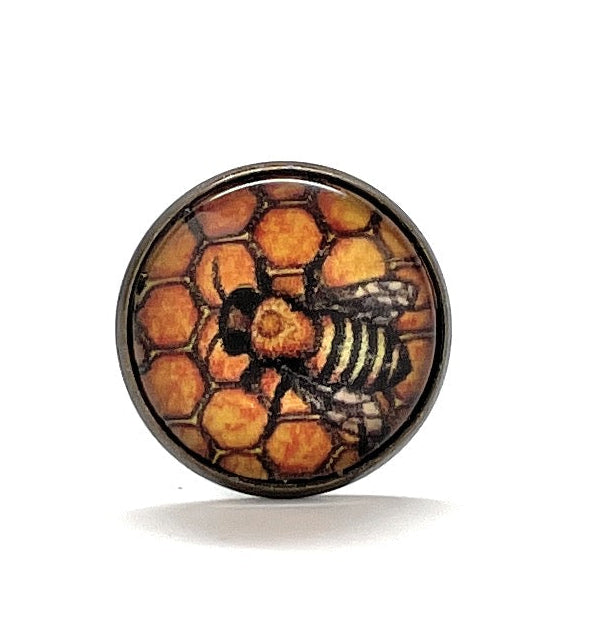 Round brooch with bee and honeycomb design on a white background