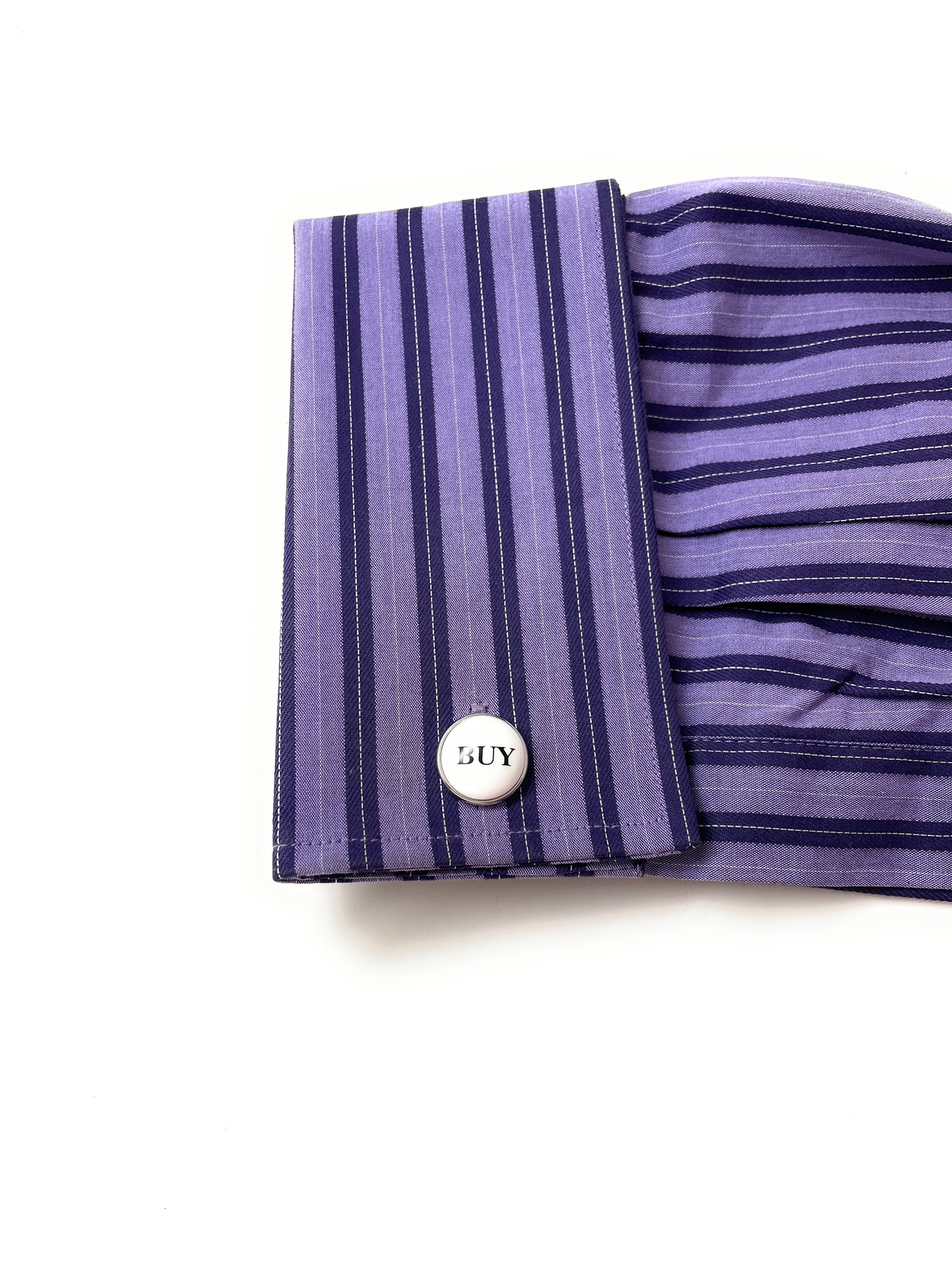 Close-up of a purple striped shirt cuff with a button labeled 'SUY' on a white background