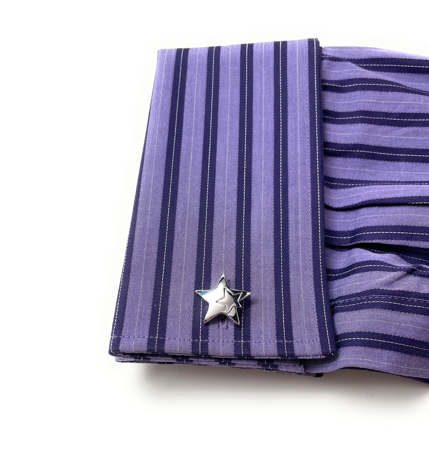 Purple striped fabric with a silver star-shaped brooch on a white background
