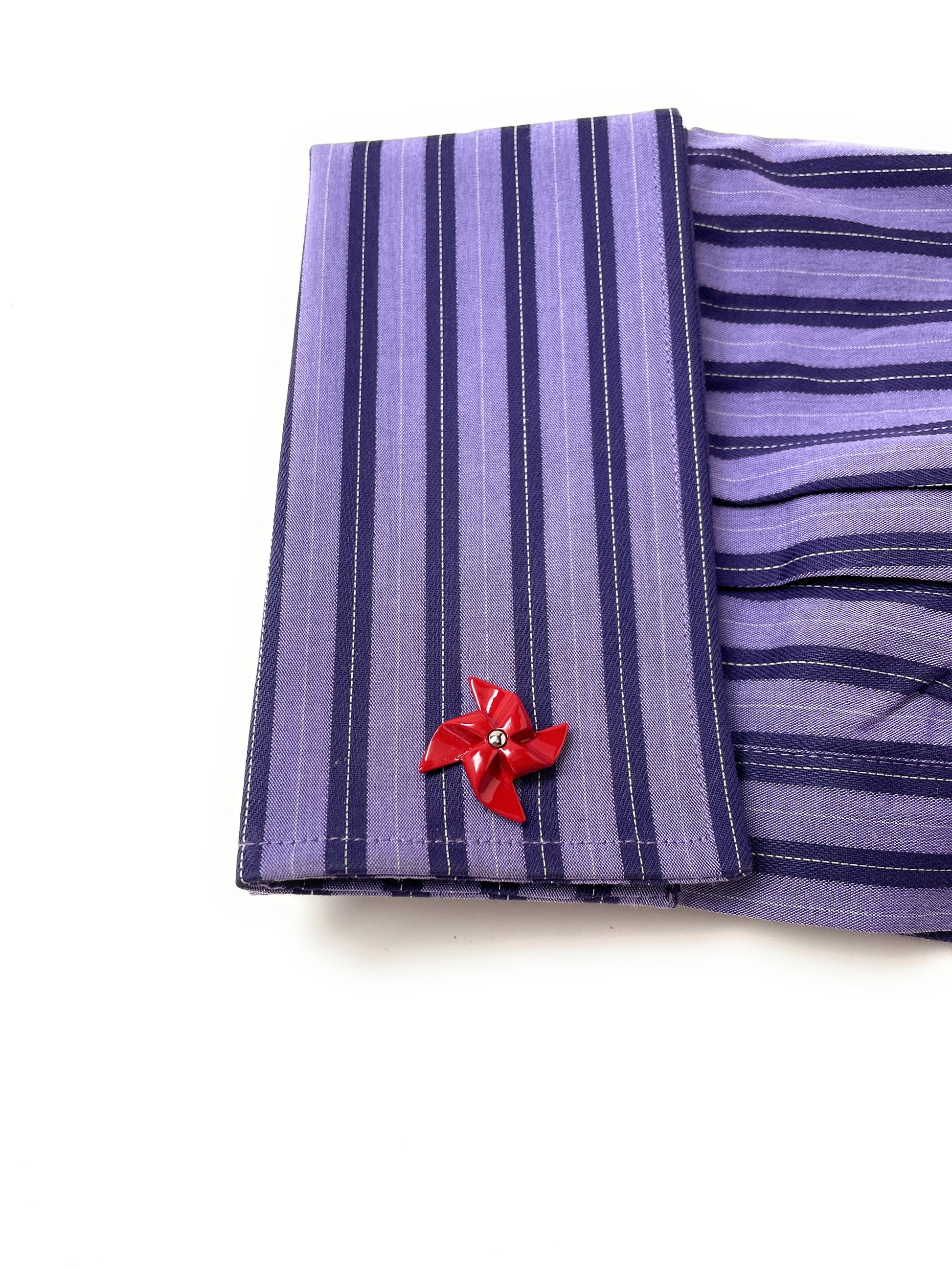 Purple striped fabric with a red flower pin on a white background