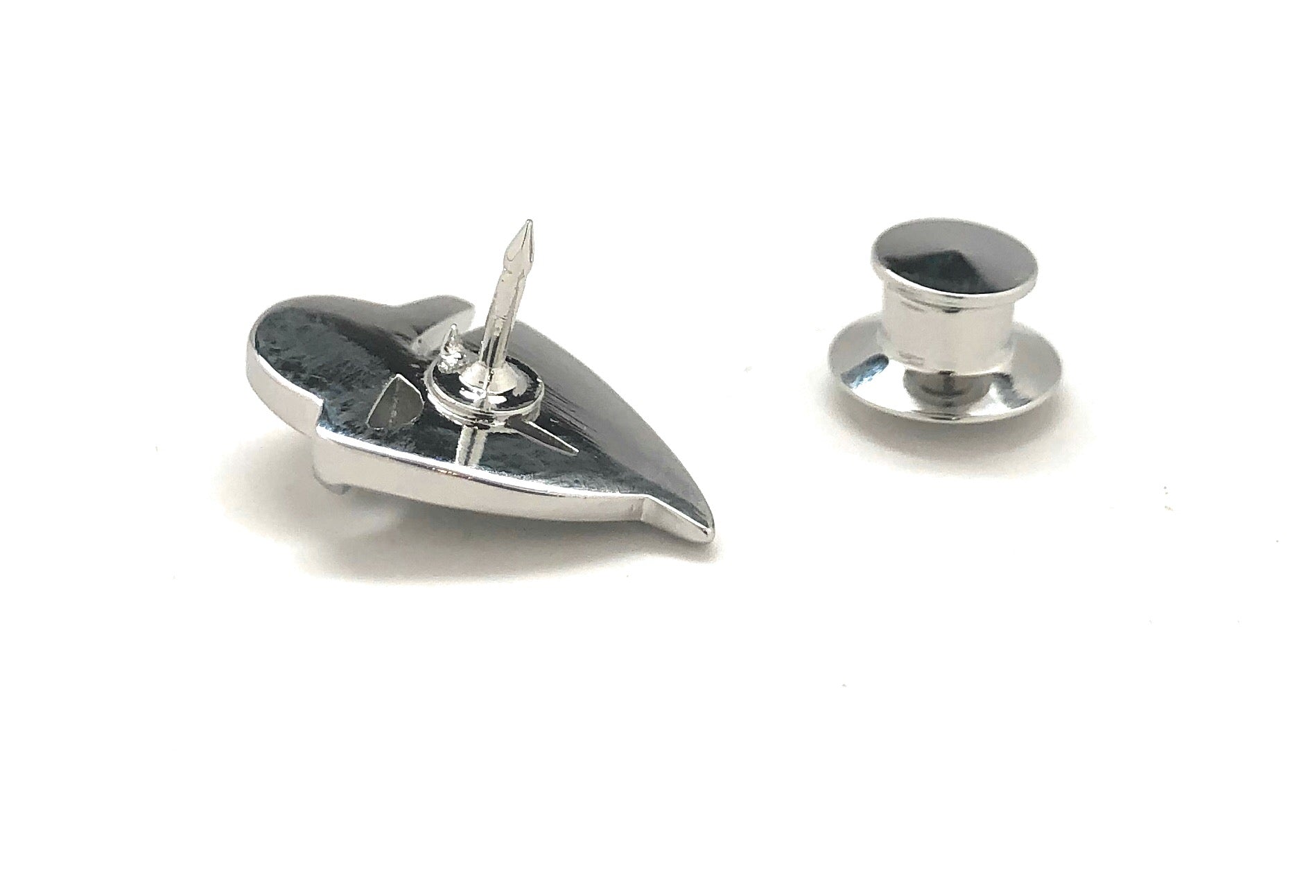 Silver pushpin and round metal object on a white background