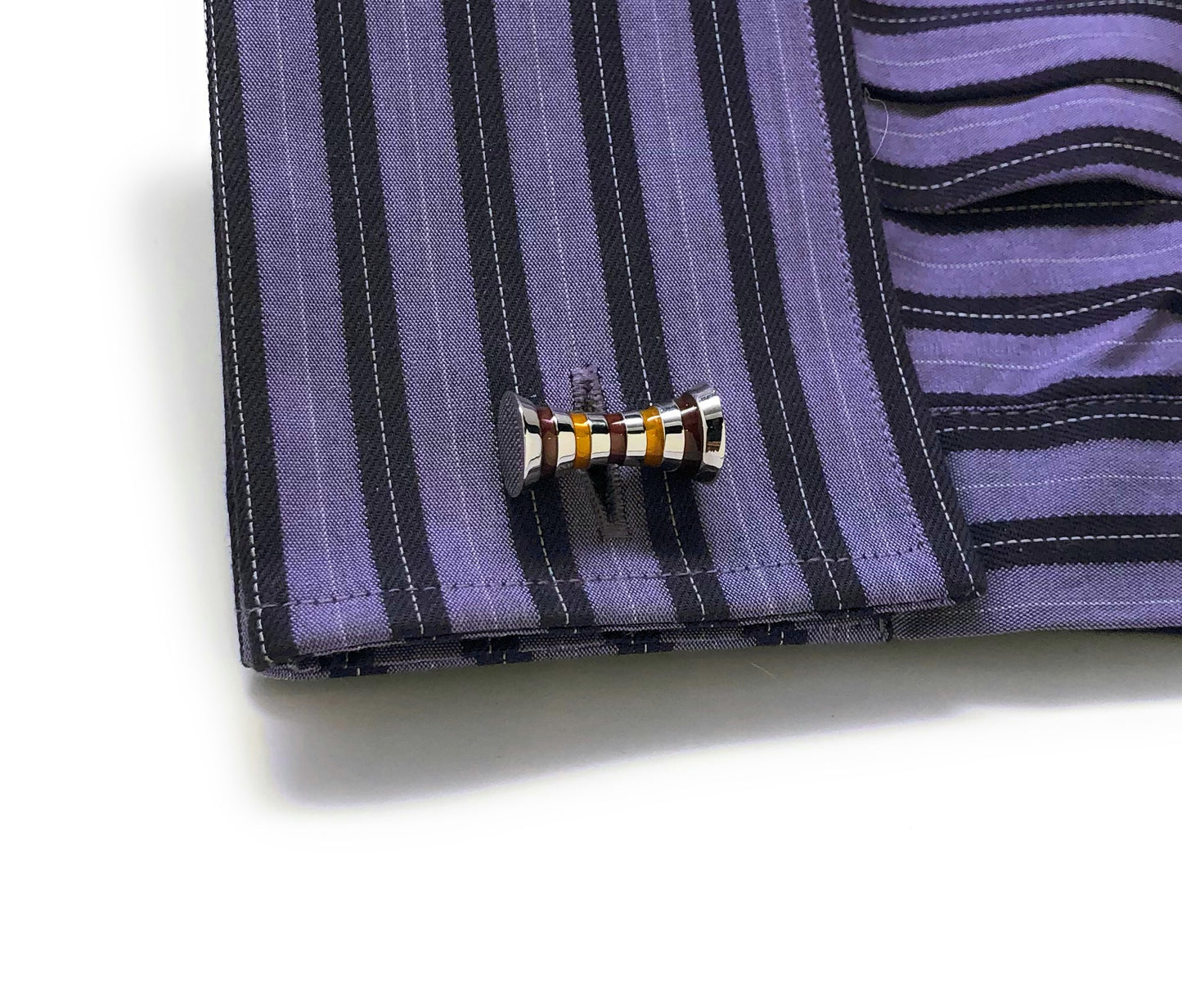 Cufflink on a striped shirt cuff with a white background