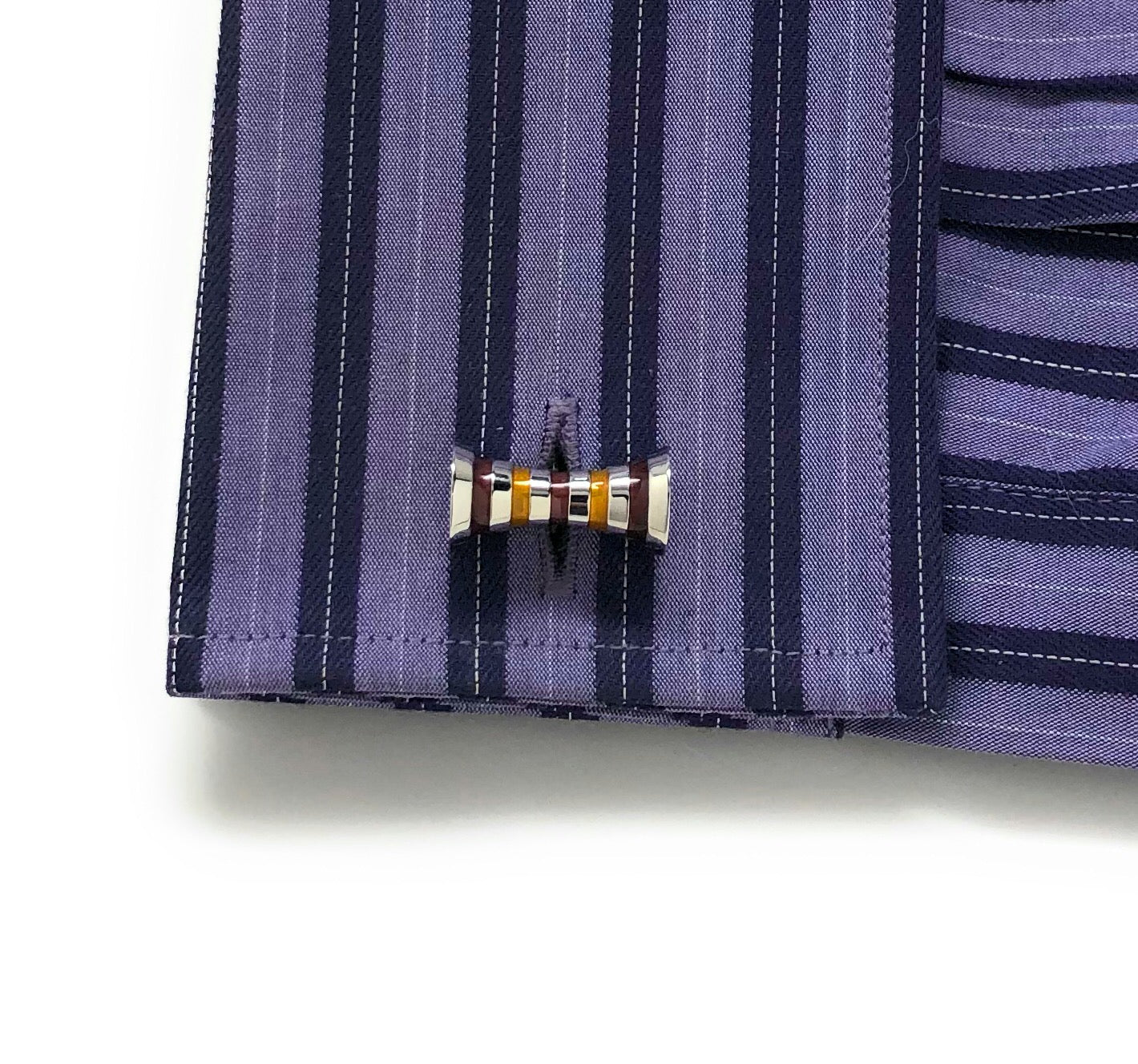 Close-up of a shirt cuff with a bow tie cufflink on a white background