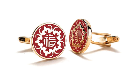 Gold cufflinks with red and white design on a white background