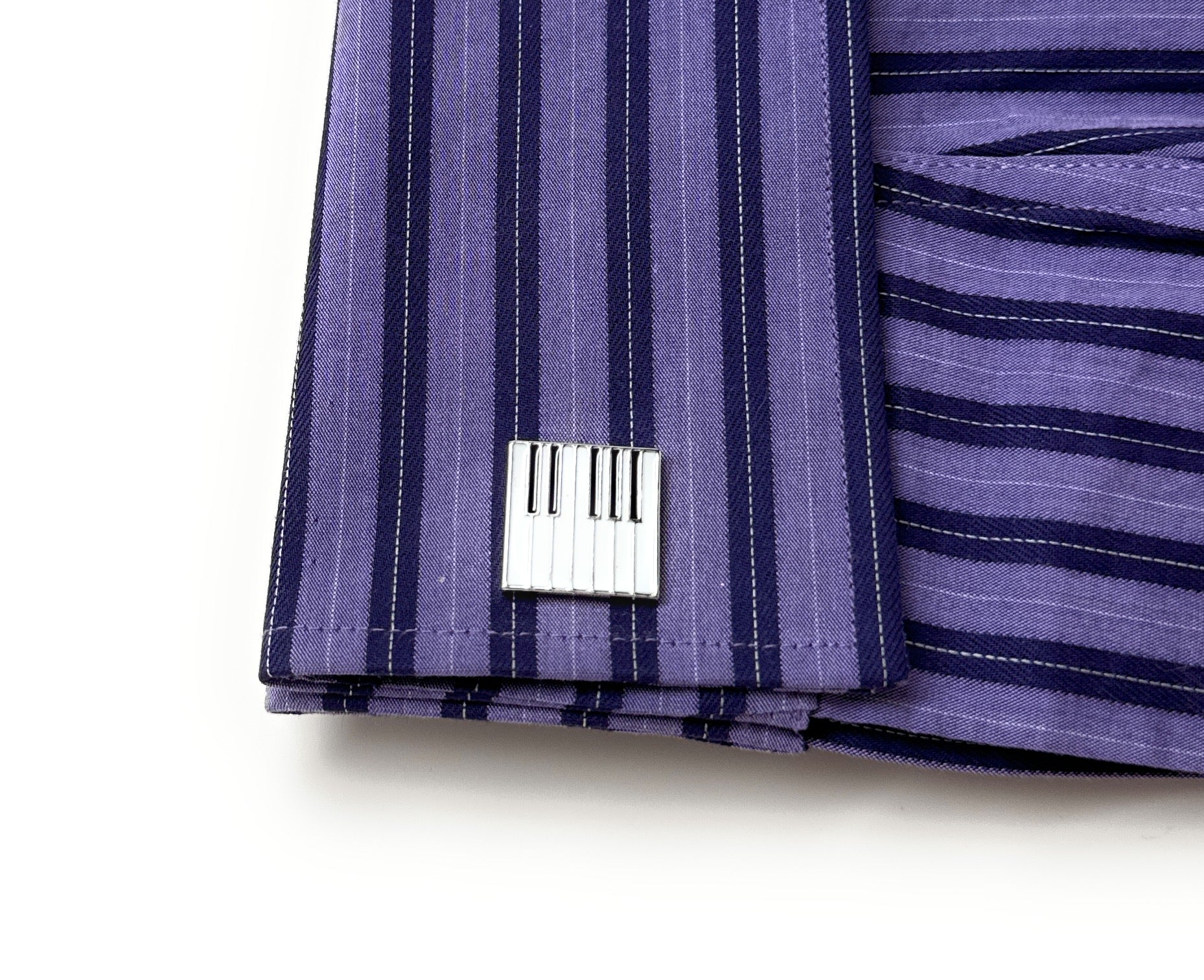 Close-up of a folded purple striped fabric with a metal tag on a white background