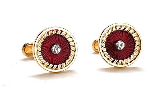Gold and red cufflinks with a central gemstone on a white background