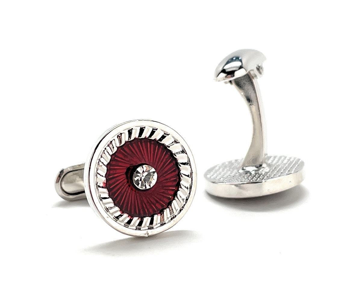 Cufflinks with a red circular design and silver accents on a white background