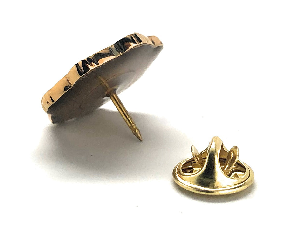 Gold pin with a textured design on a white background