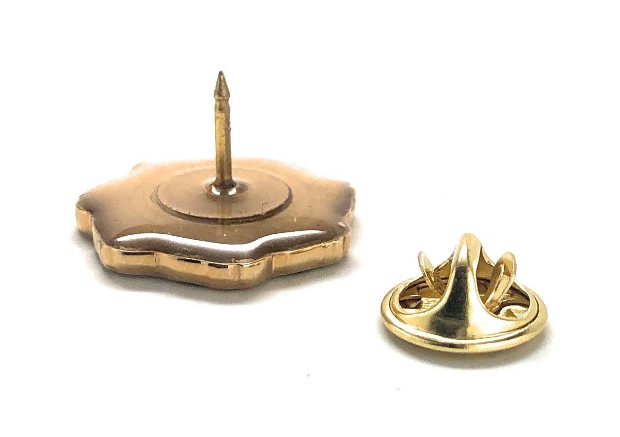 Gold metal badge with a central pin on a white background