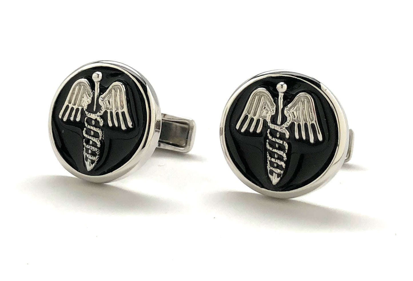 Pair of cufflinks with a black circular design featuring a silver emblem on a white background