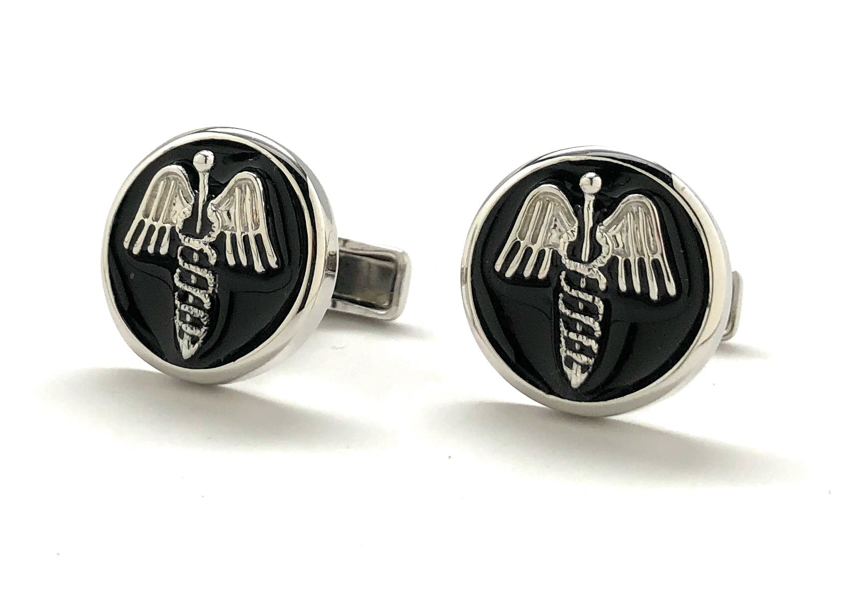 Pair of cufflinks with a black circular design featuring a silver emblem on a white background
