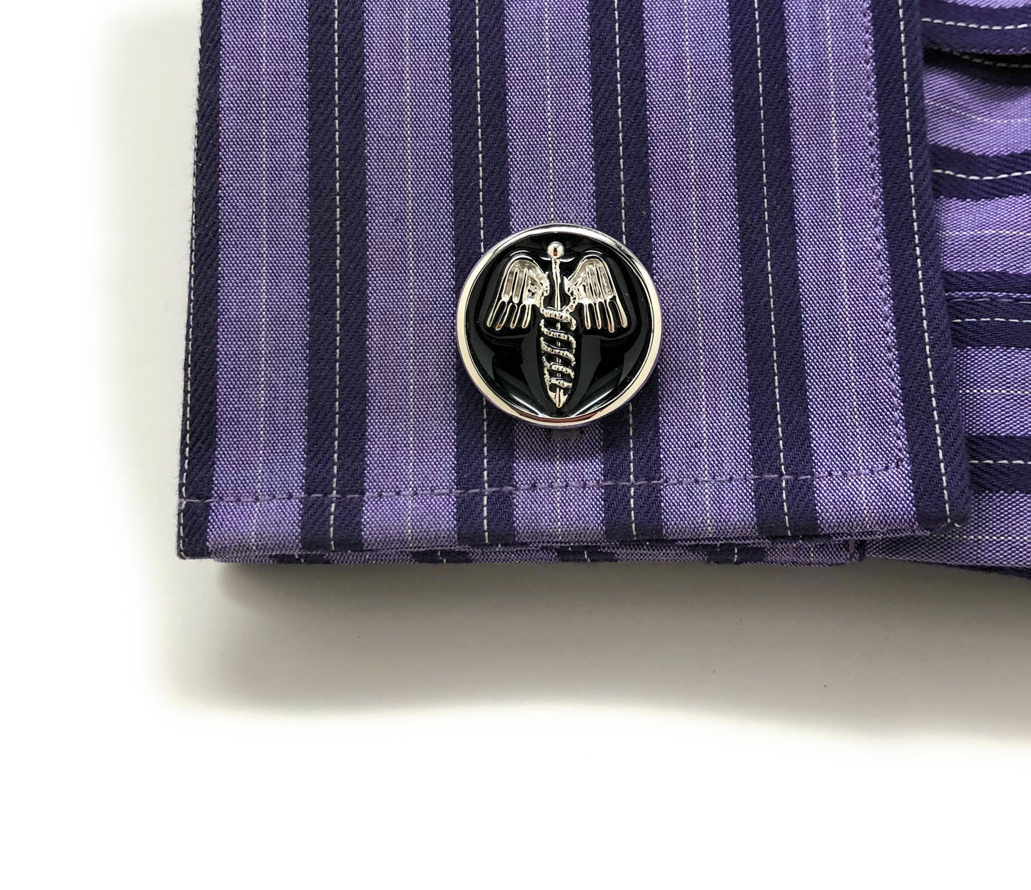 Close-up of a purple striped shirt cuff with Caduceus emblem cufflinks for physicians and medical professionals