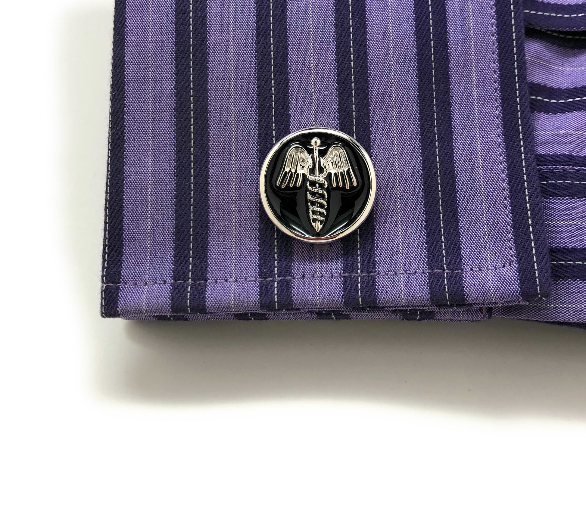 Close-up of a purple striped shirt cuff with Caduceus emblem cufflinks for physicians and medical professionals