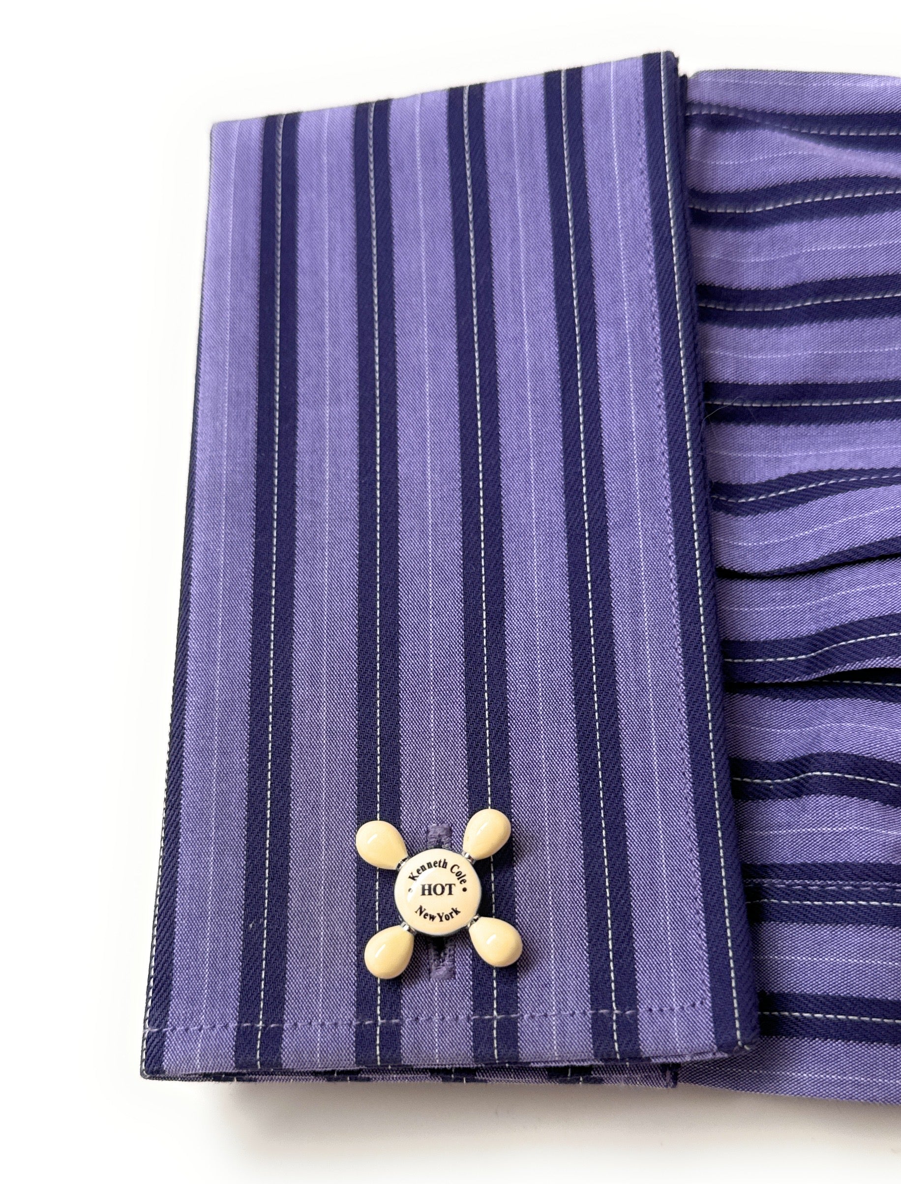 Purple striped fabric with a yellow button featuring text on a white background