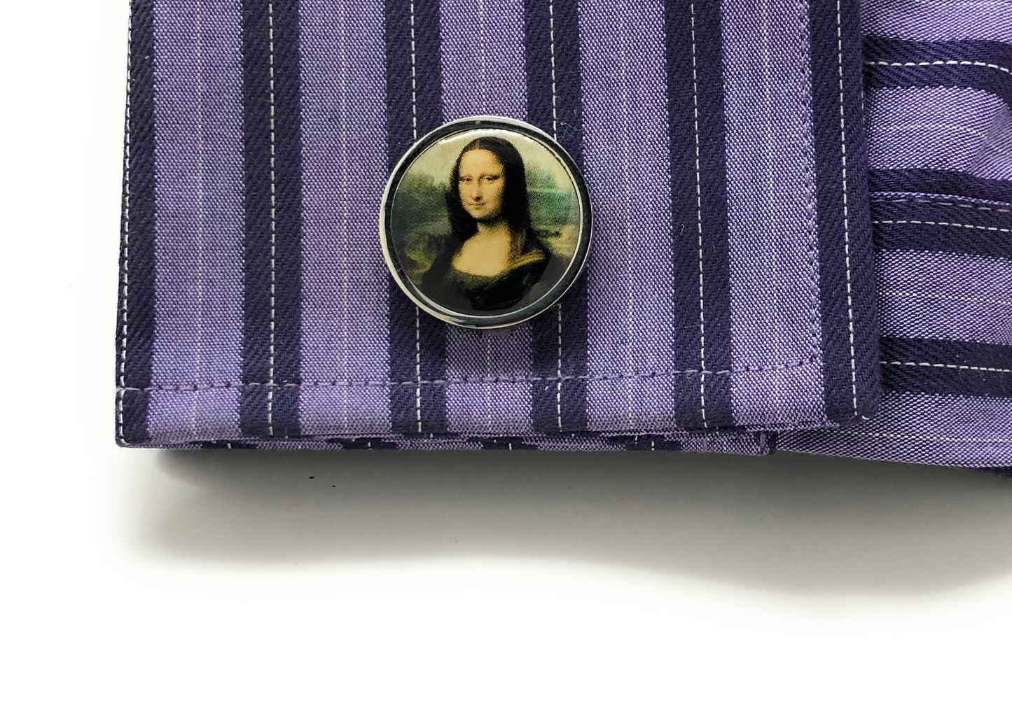Close-up of a shirt cuff with a button featuring the Mona Lisa on a purple striped background