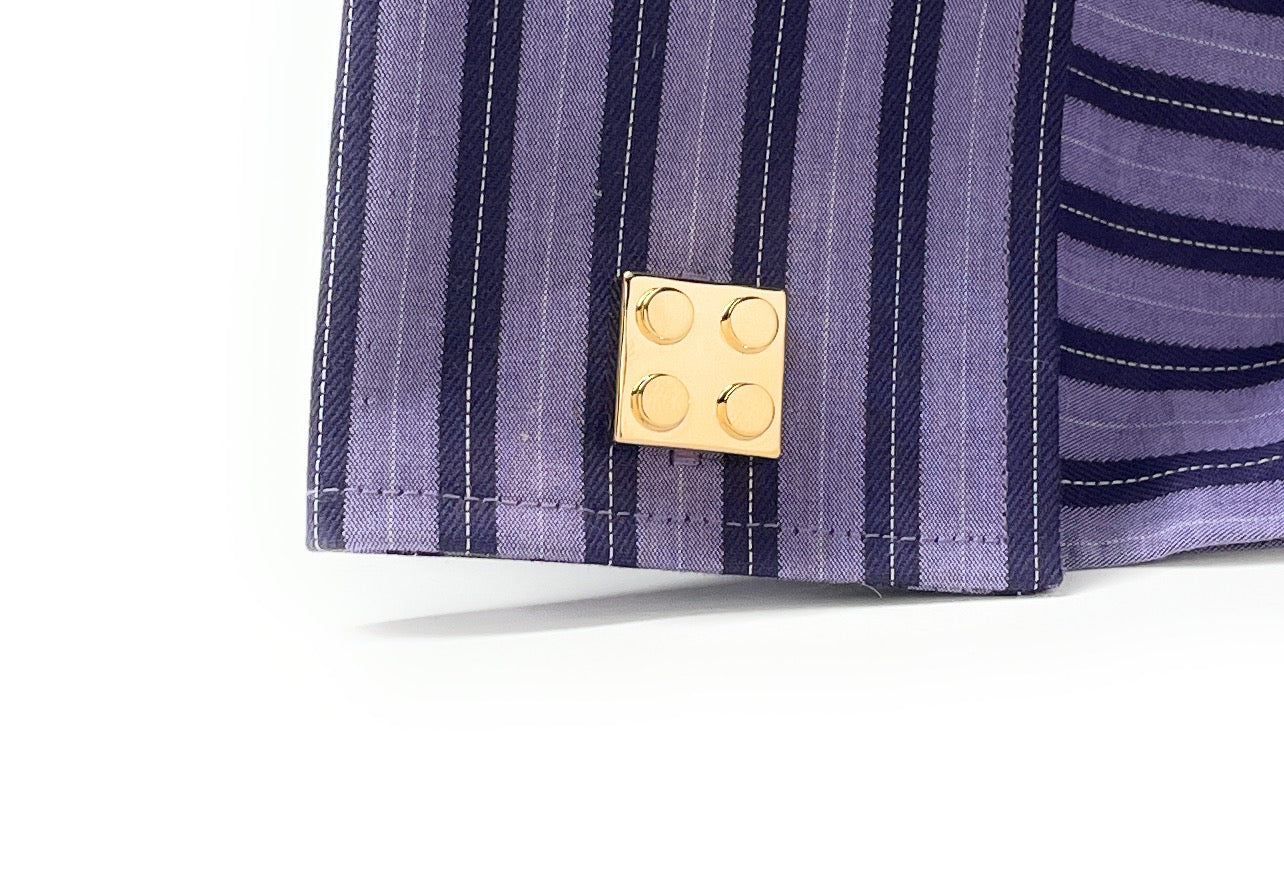 Close-up of a purple striped fabric with a gold button on a white background