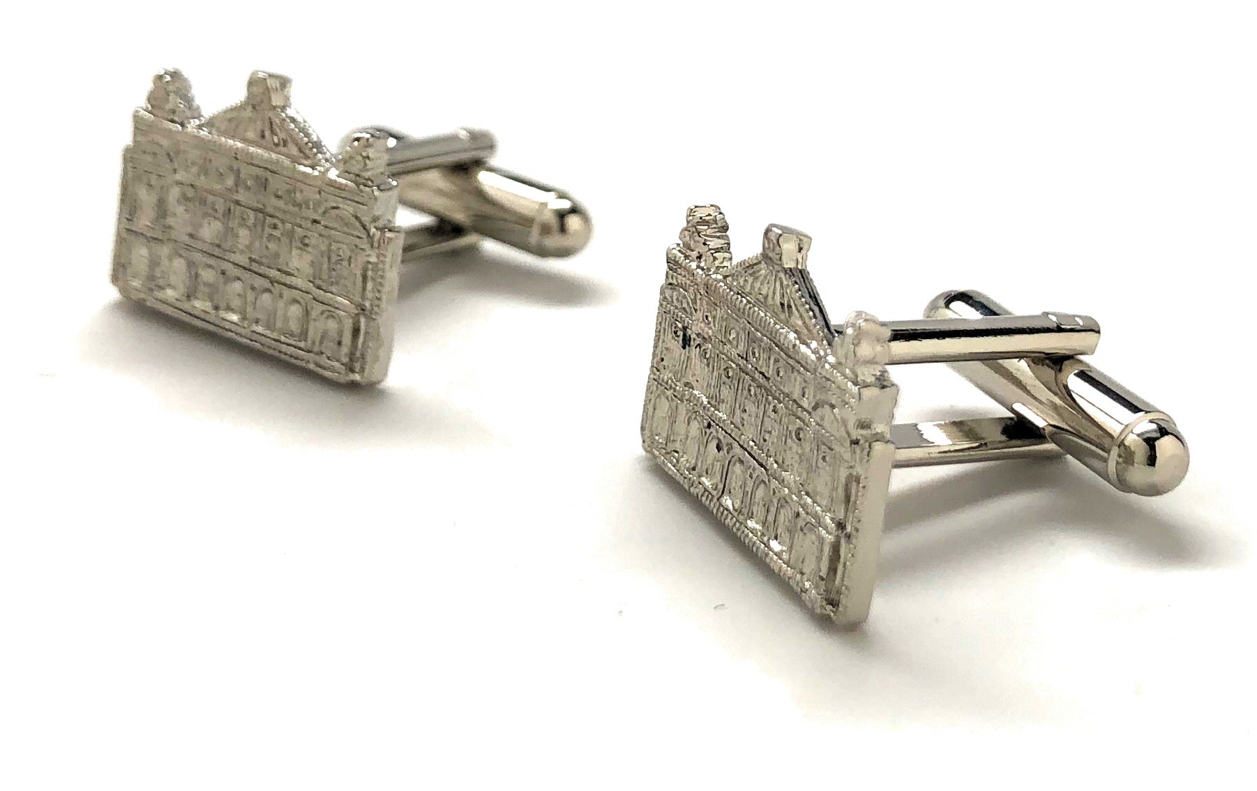 Silver cufflinks shaped like a building on a white background