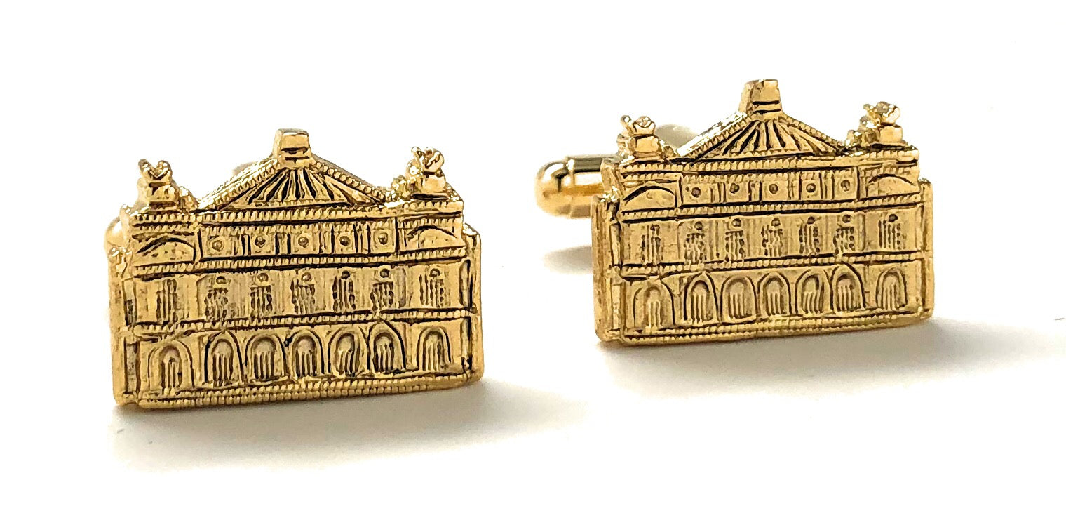 Gold cufflinks shaped like a building on a white background