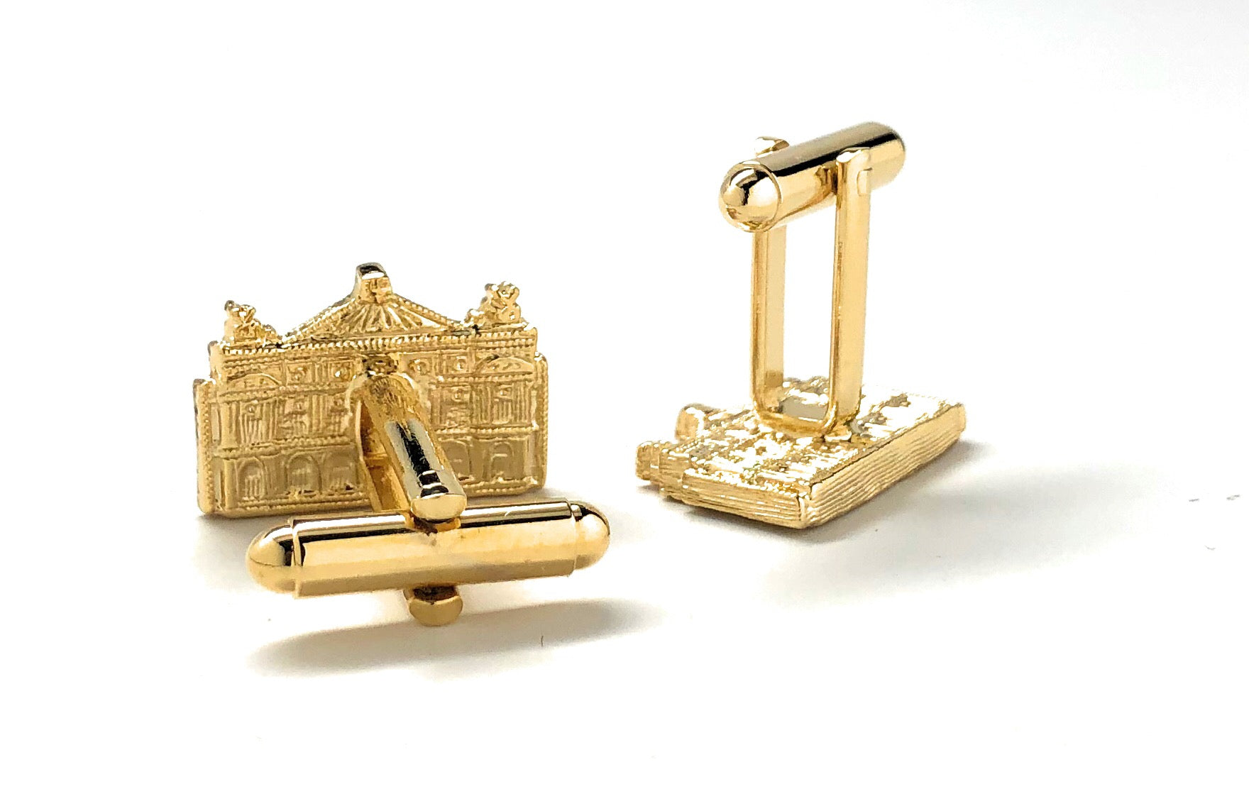 Gold cufflinks with architectural design on a white background