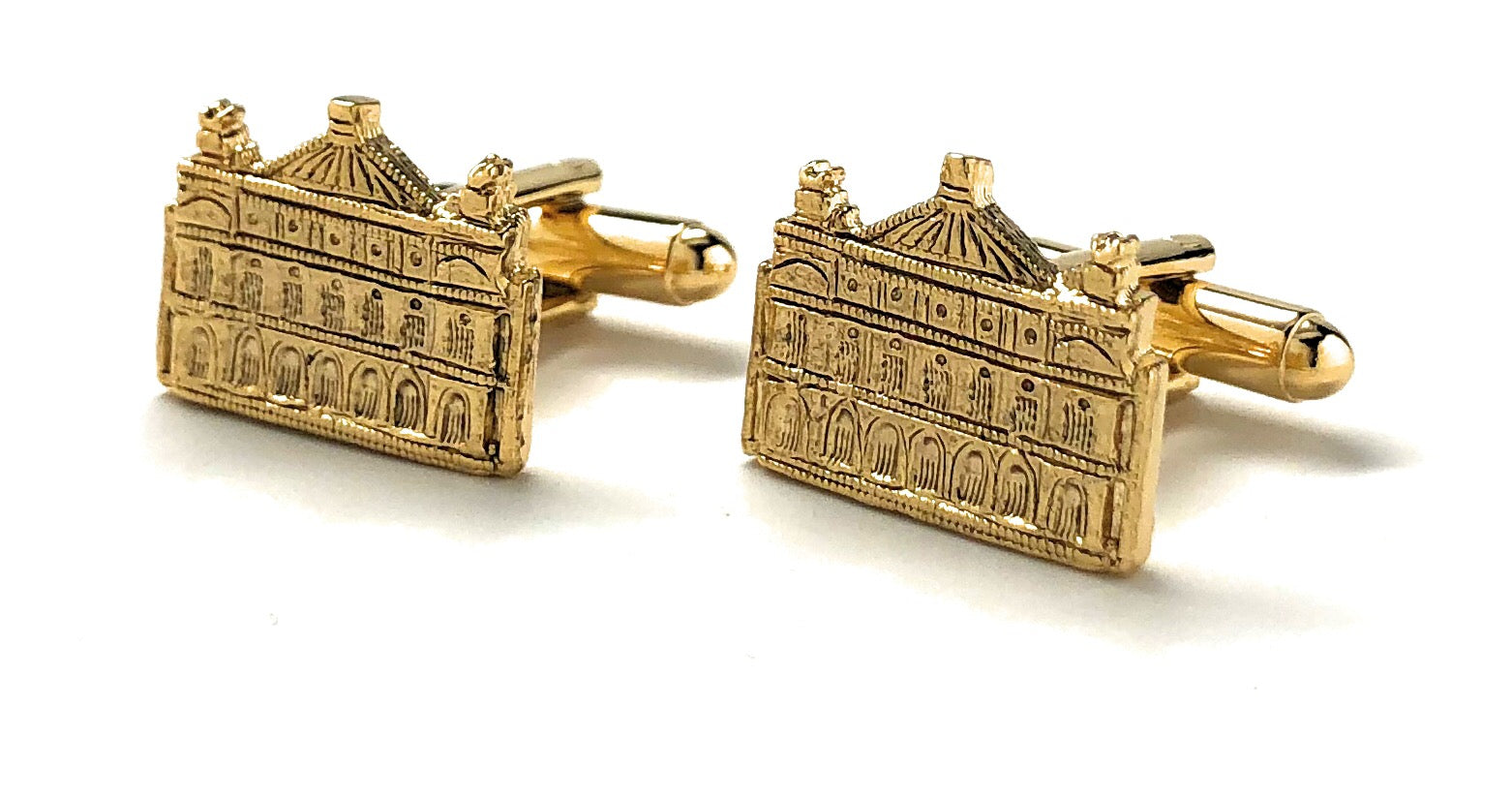 Gold cufflinks with architectural design on a white background