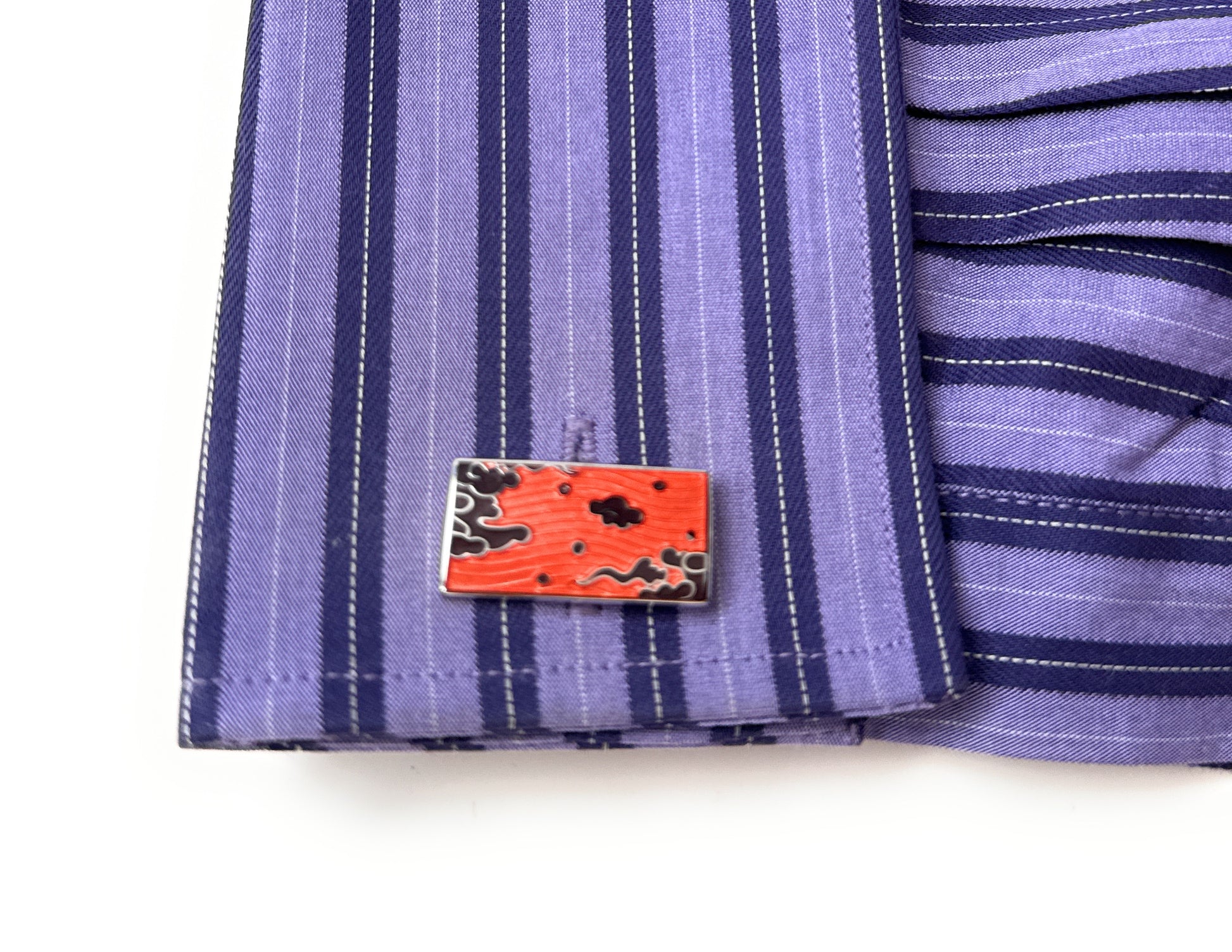 Close-up of a purple striped fabric with a red and black patterned label.