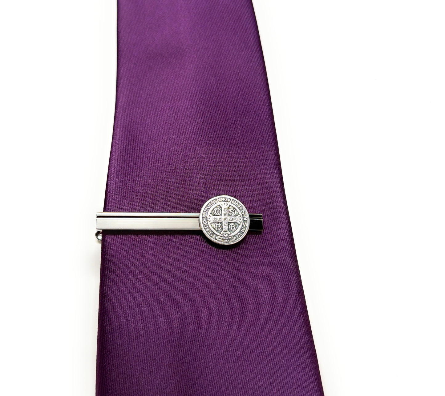 Silver tie clip on a purple tie against a white background