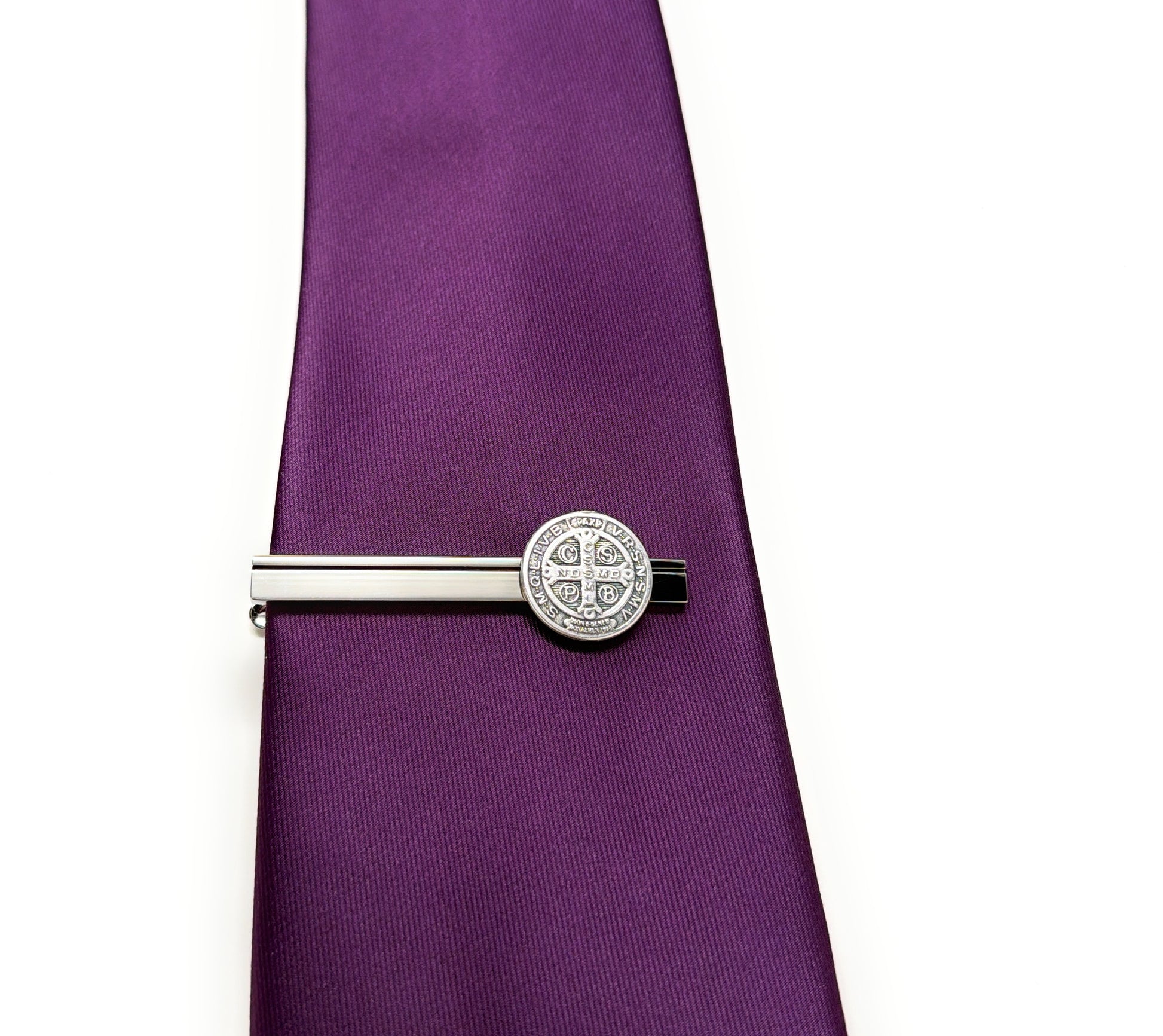 Silver tie clip on a purple tie against a white background