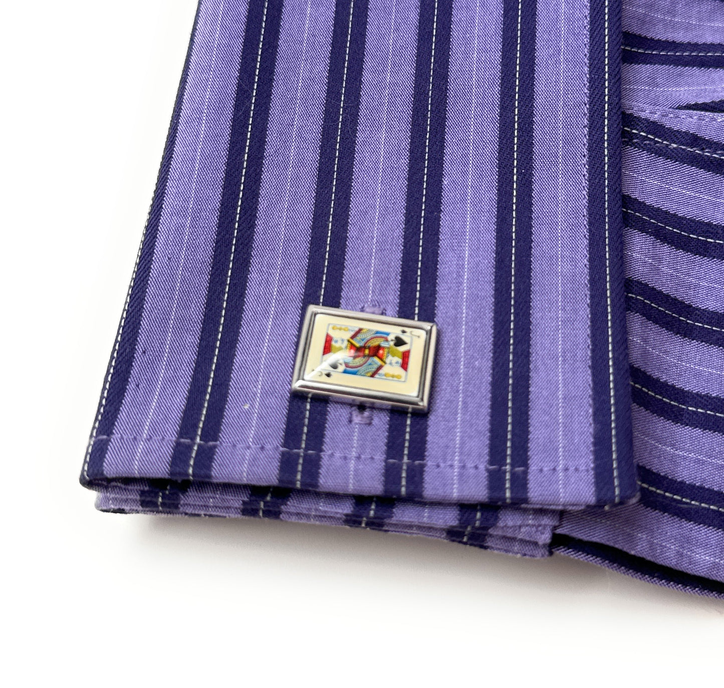Purple striped fabric with a decorative metal pin on a white background