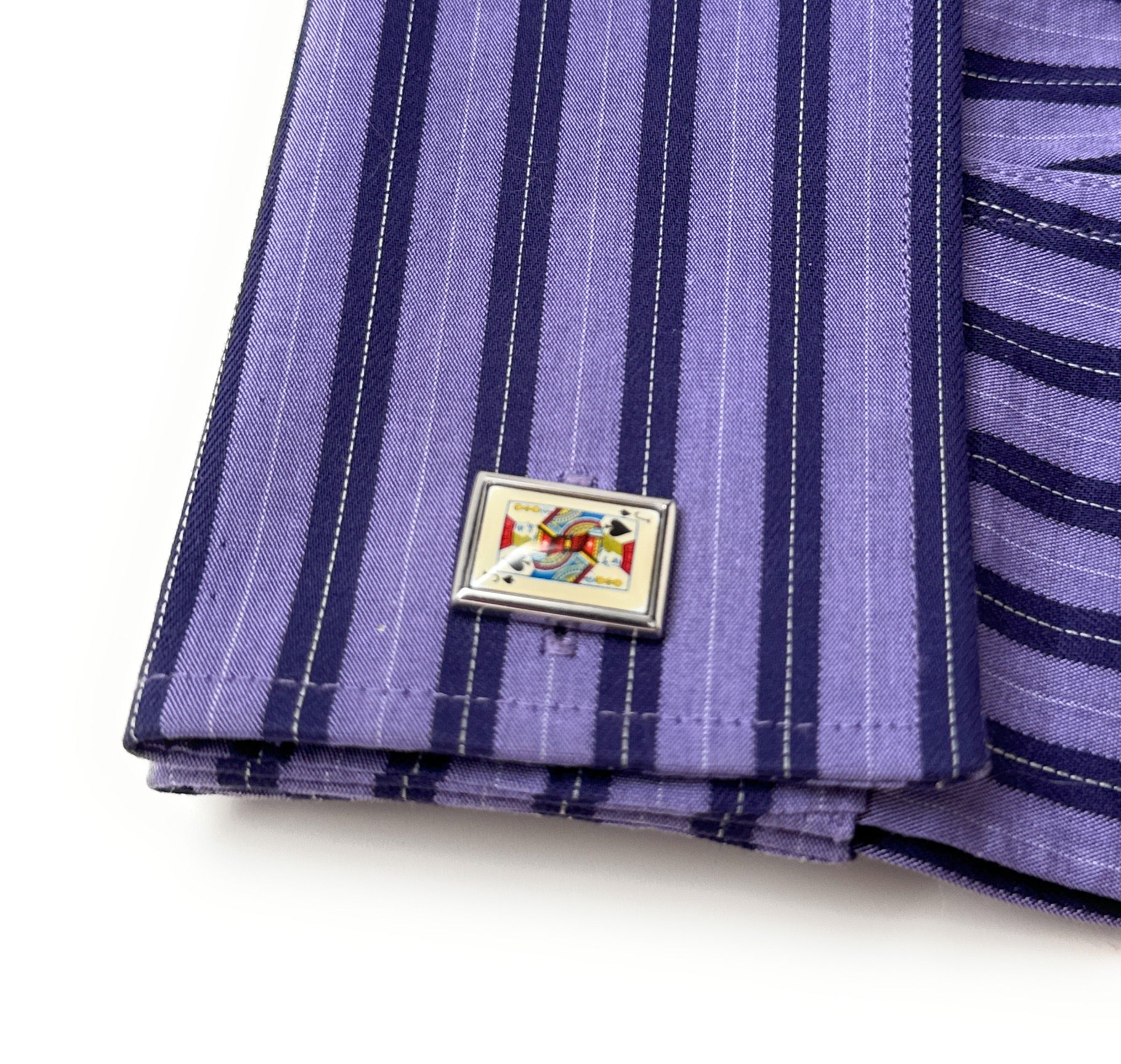 Purple striped fabric with a decorative metal pin on a white background