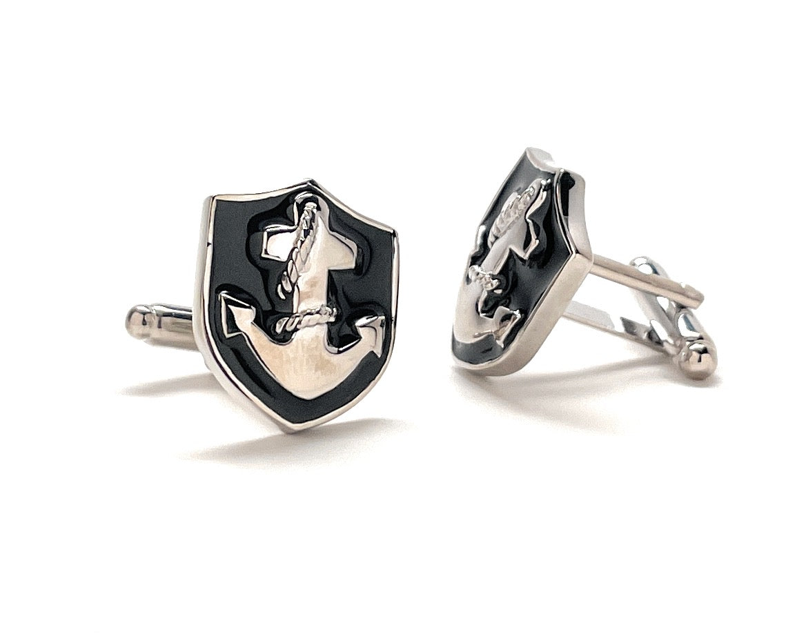 Silver and black cufflinks with a shield design on a white background