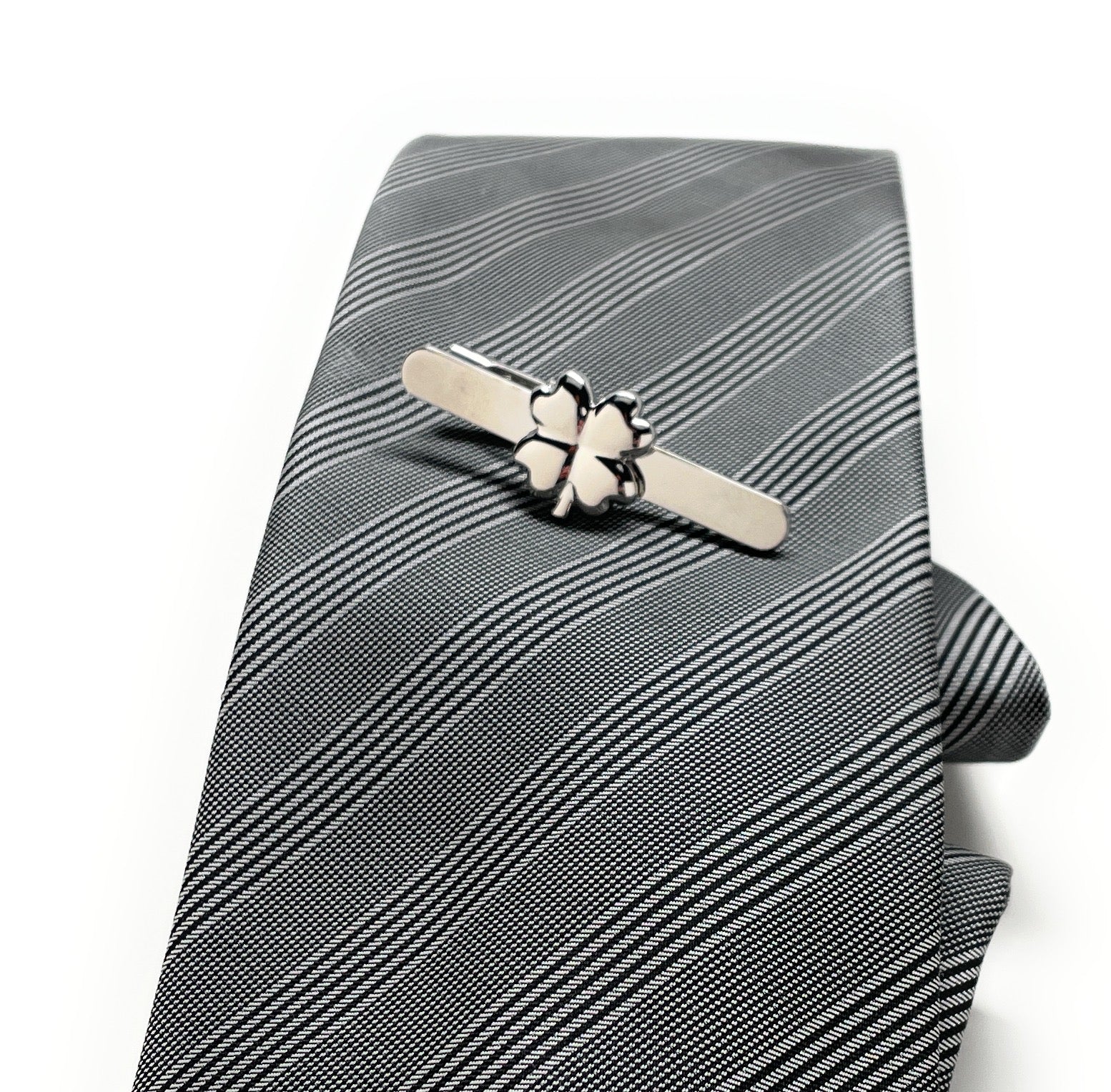 Gray striped tie with a silver tie clip on a white background