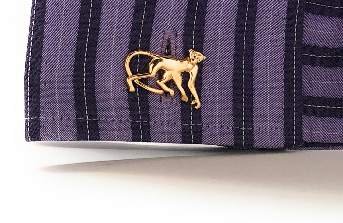 Gold monkey cufflink on a striped fabric background