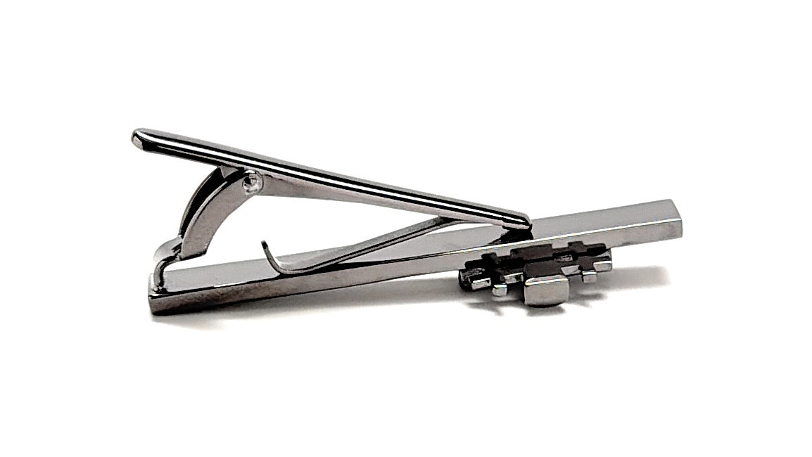 A polished silver metal tie clip with a rectangular bar and spring-loaded lever, shown on a clean white background.