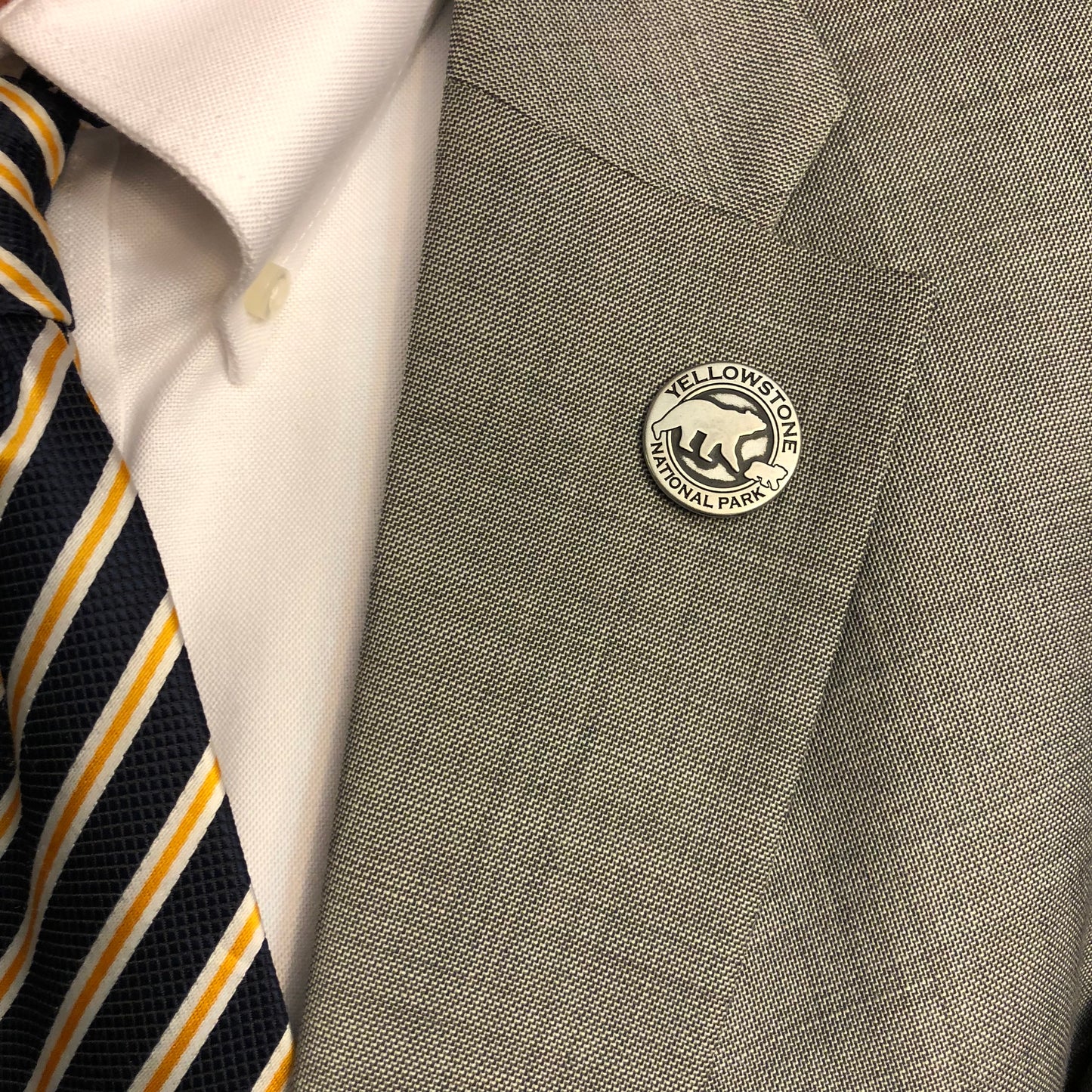 Gray shirt with a Yellowstone National Park button and a striped tie.