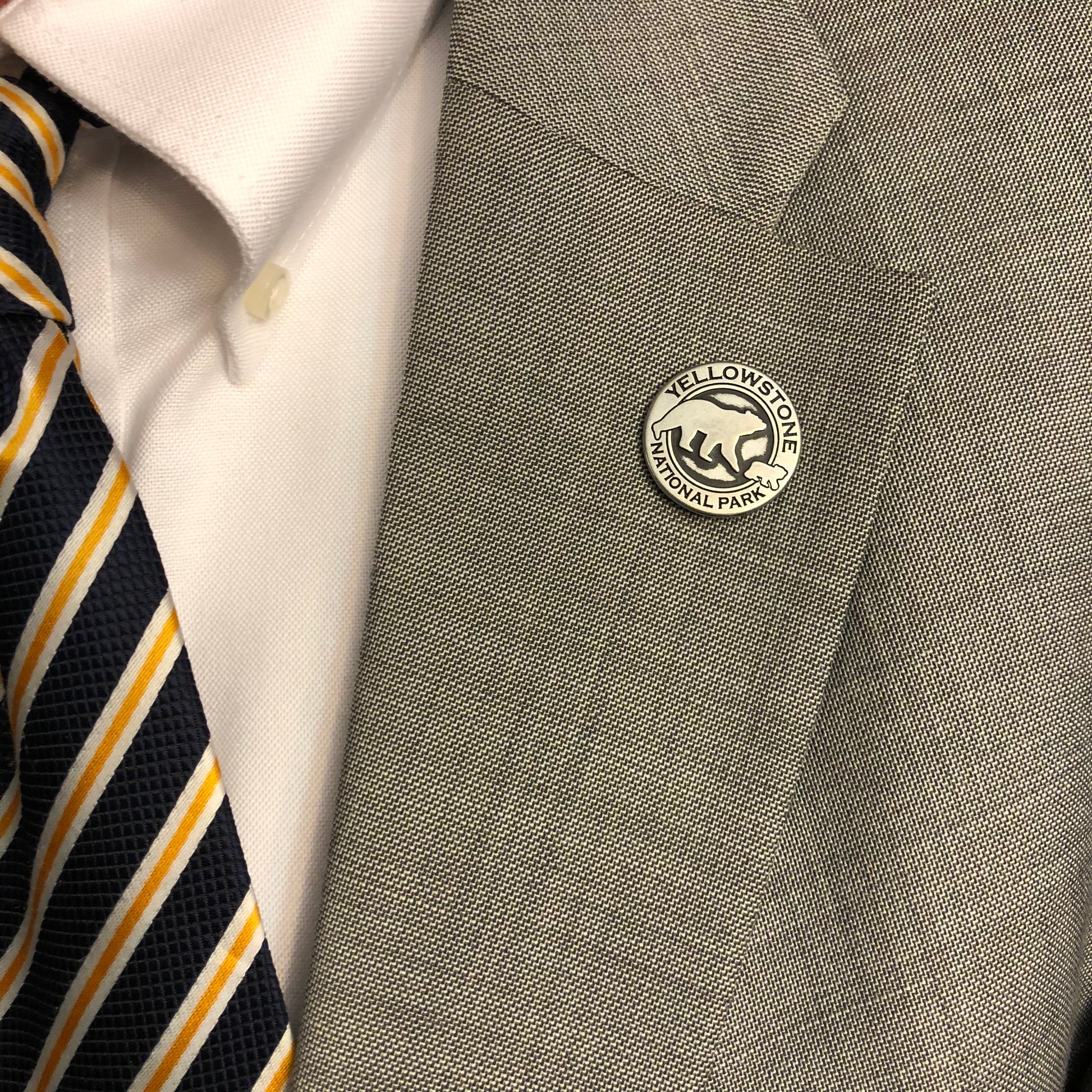 Gray shirt with a Yellowstone National Park button and a striped tie.
